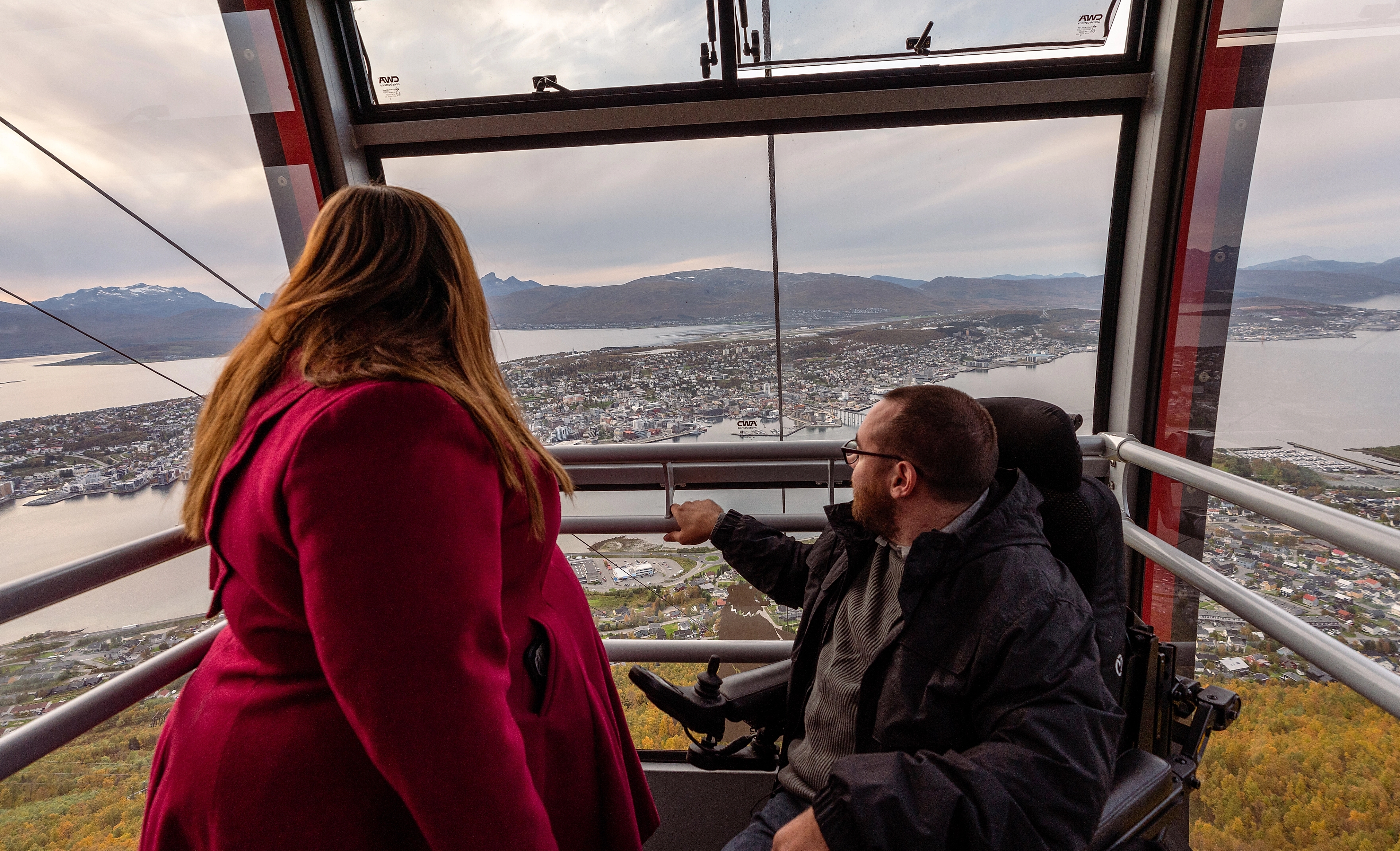 A woman and a handicapped man taking the cable car up to the mountain Storsteinen in Tromsø