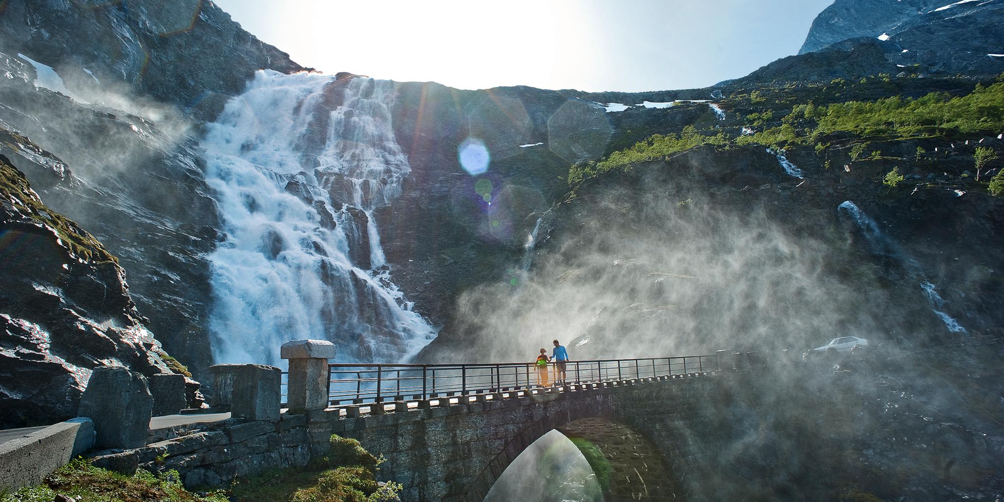 Two people running over a bridge at the Trollstigen road, in Rauma