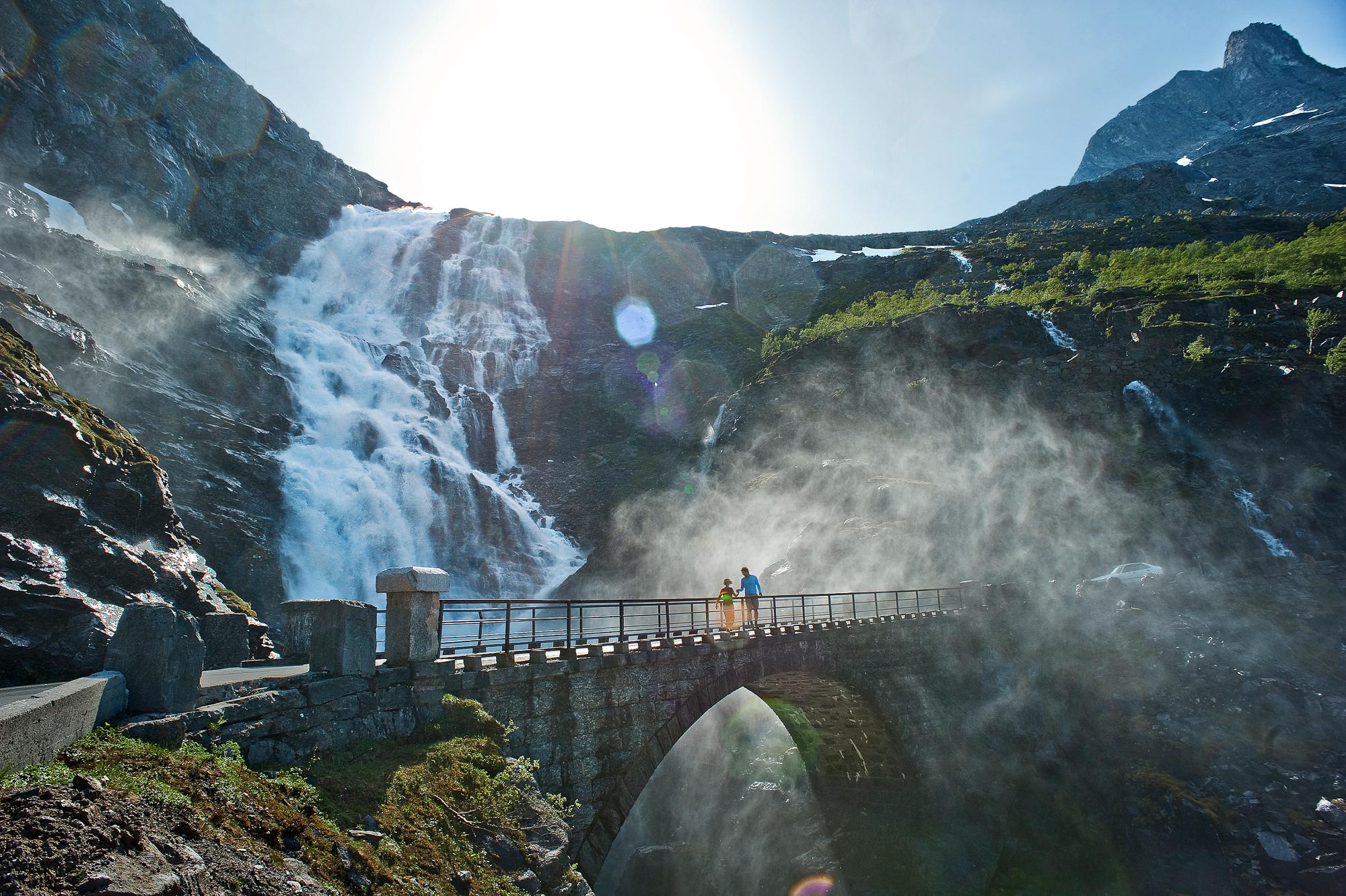 Two people running over a bridge at the Trollstigen road, in Rauma