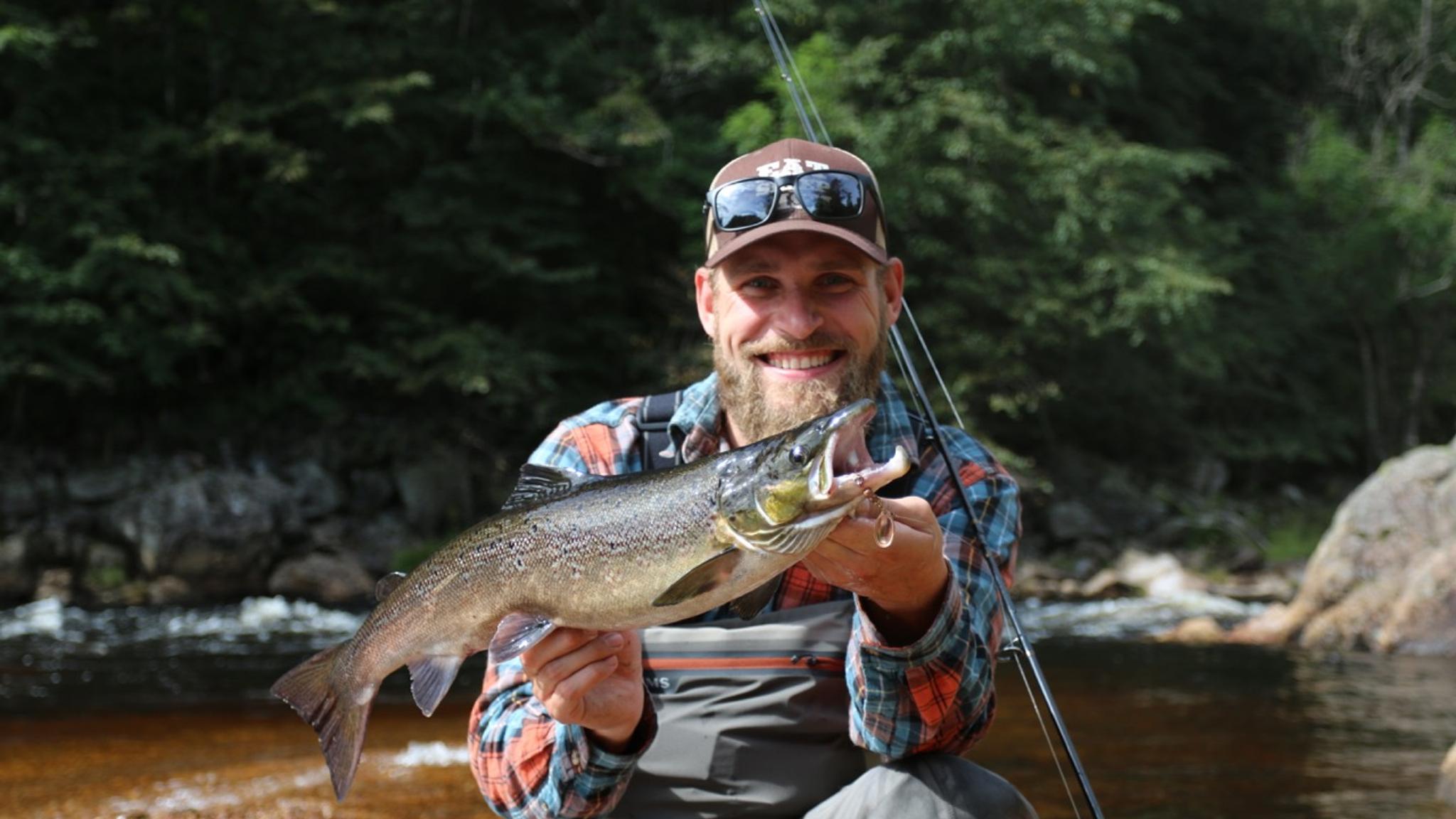 An angler is holding a salmon in Mandal, Southern Norway