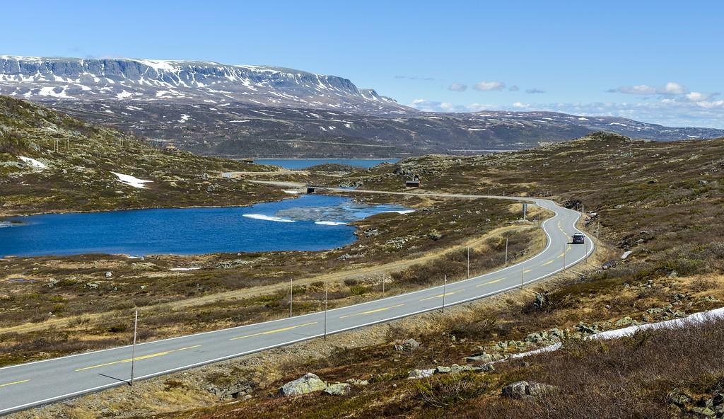 A car driving past lakes on a mountain plateau