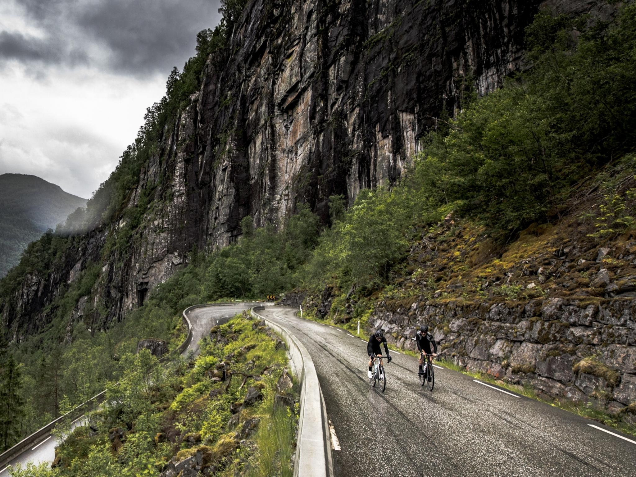 En grupp cyklister på en slingrande väg i regionen Fjord Norge (Vestlandet)