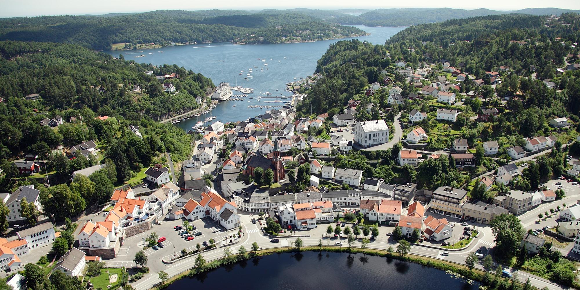 Den idylliske hvite sørlandsbyen Tvedestrand fra luften, mellom fjorden og innsjøen Tjenna.