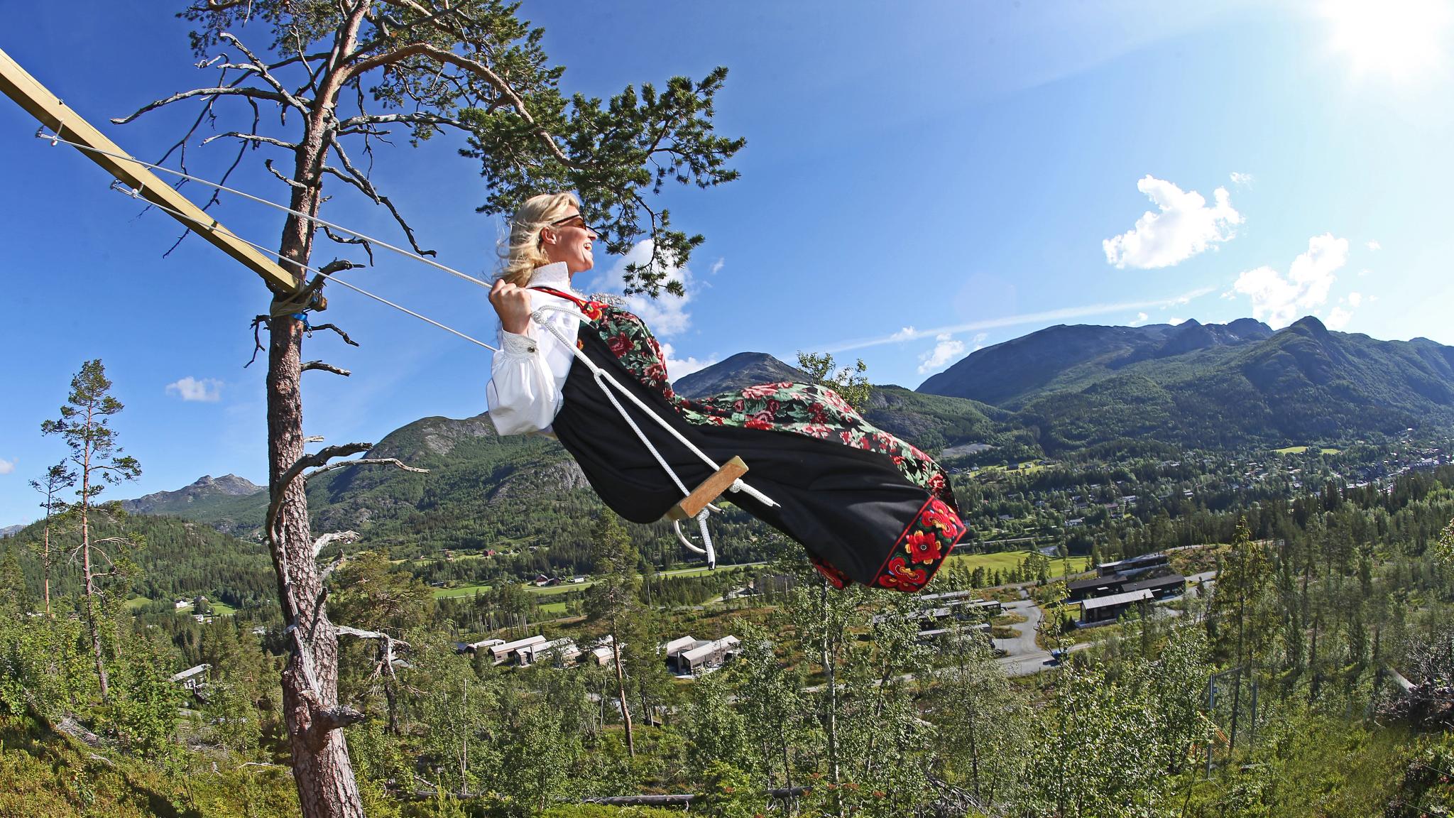 A woman is sitting on a swing while wearing the traditional costume "bunad" from Hemsedal, Eastern Norway