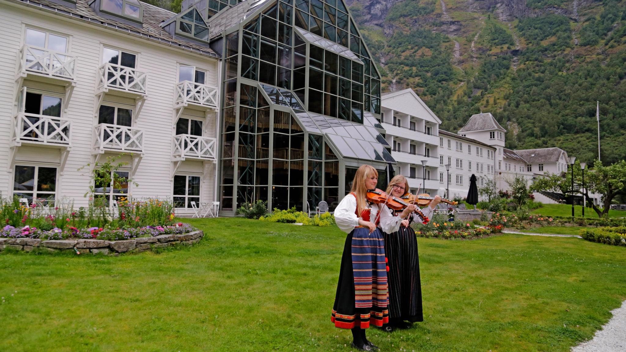 Två flickor i folkdräkter som spelar violin i Flåm i Fjord-Norge