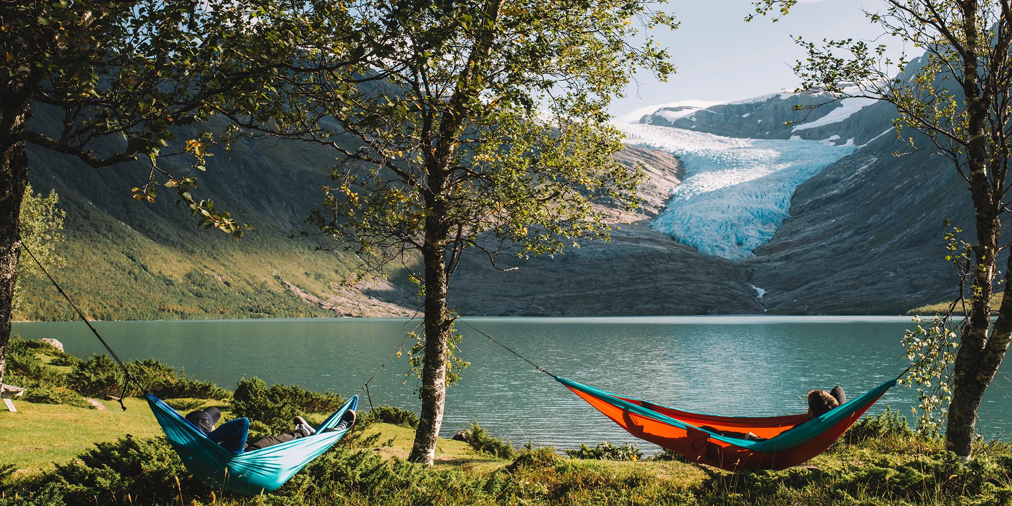 People in hammocks in front of the Svartisen glacier in Helgeland, Northern Norway