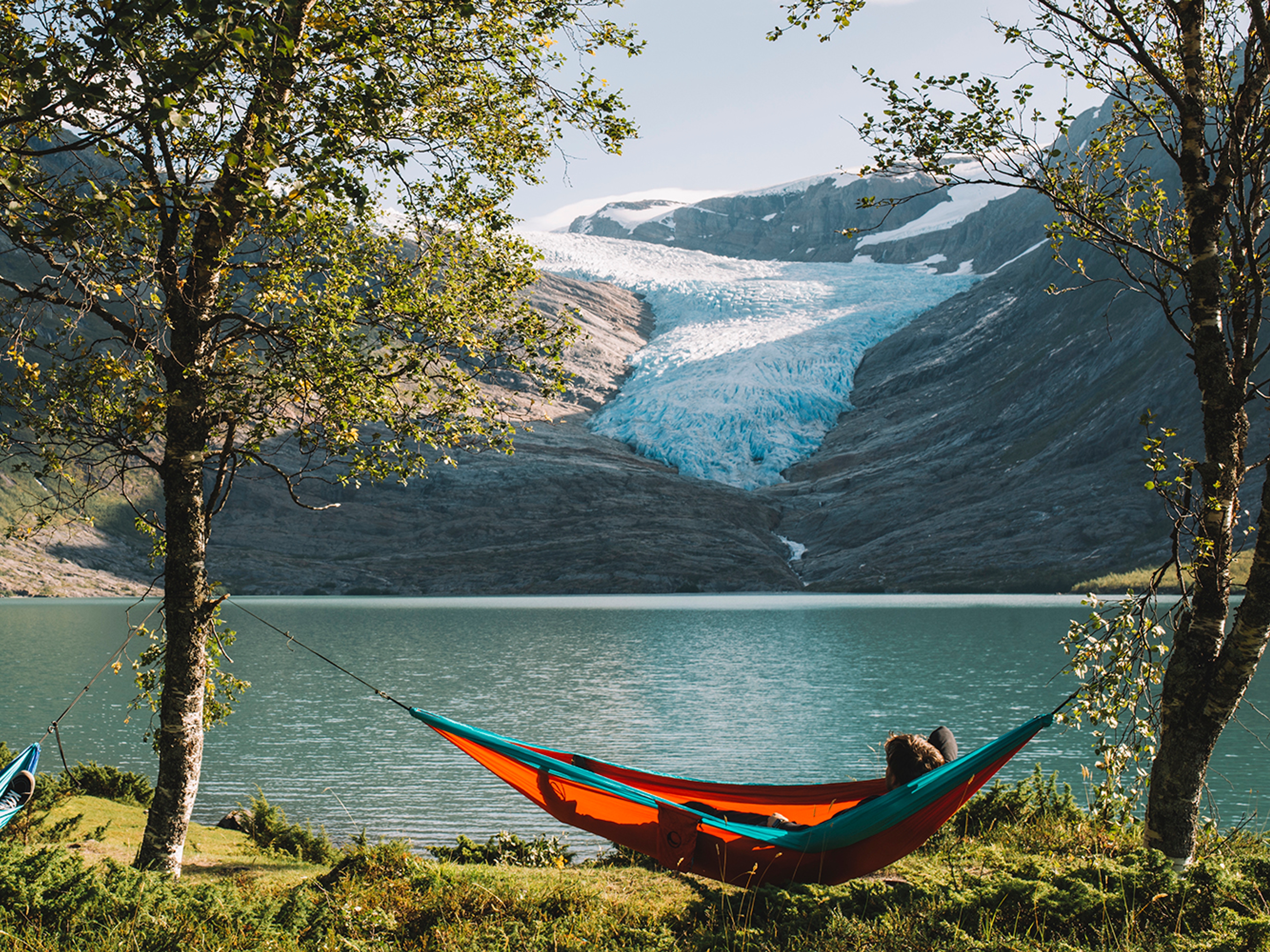 People in hammocks in front of the Svartisen glacier in Helgeland, Northern Norway