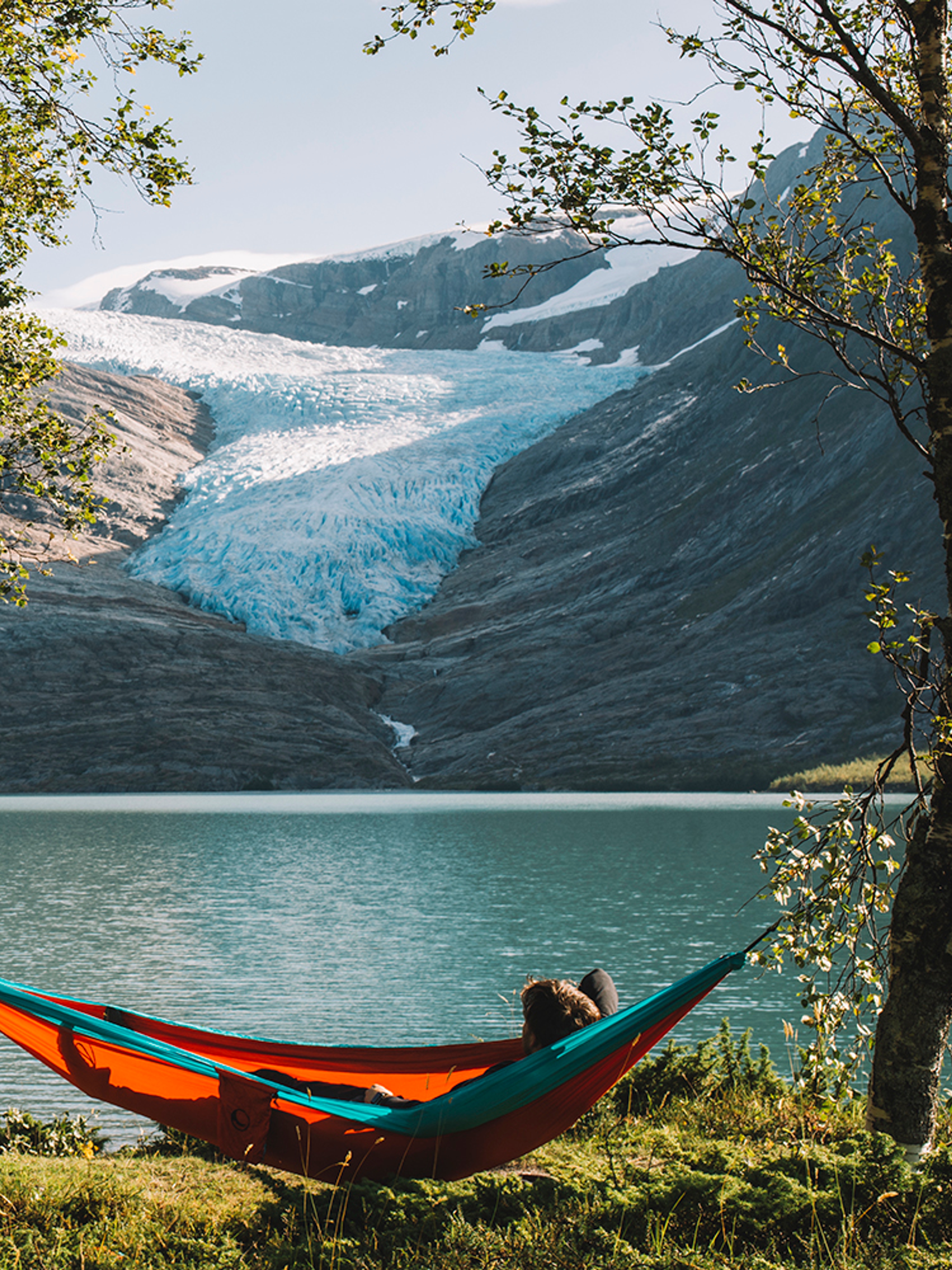 People in hammocks in front of the Svartisen glacier in Helgeland, Northern Norway