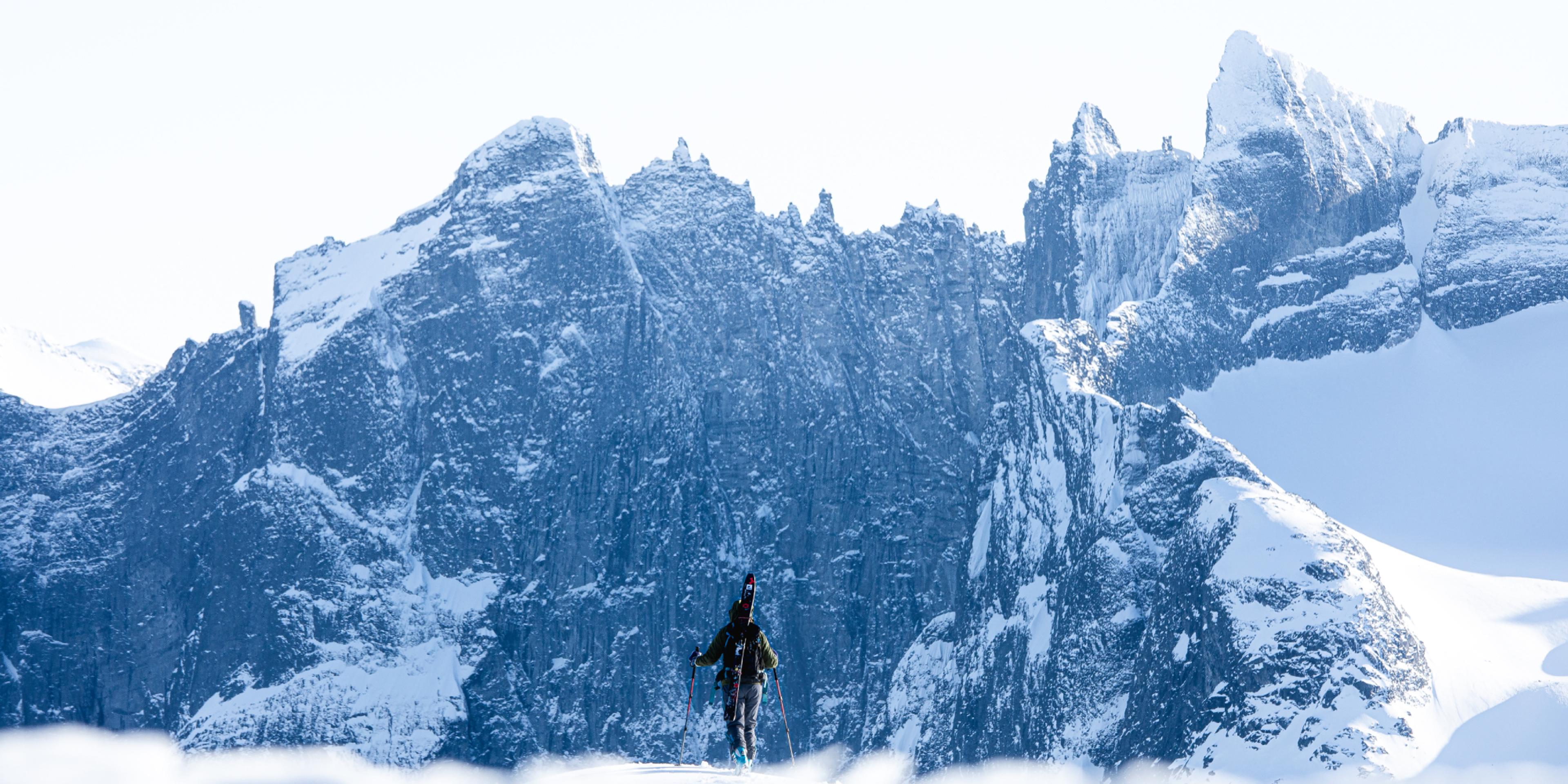 A person with skies looking at Trollveggen in Winter
