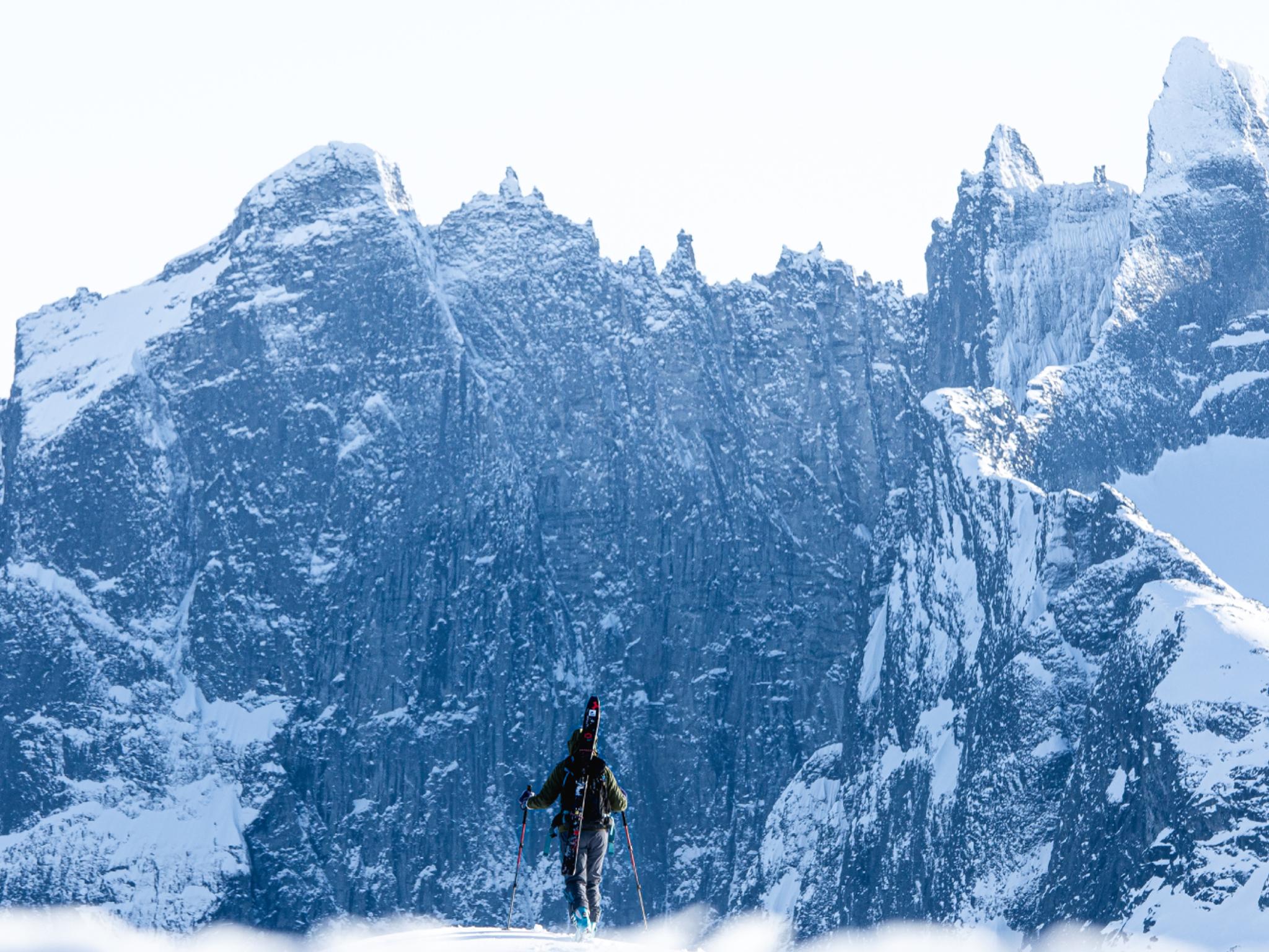 A person with skies looking at Trollveggen in Winter