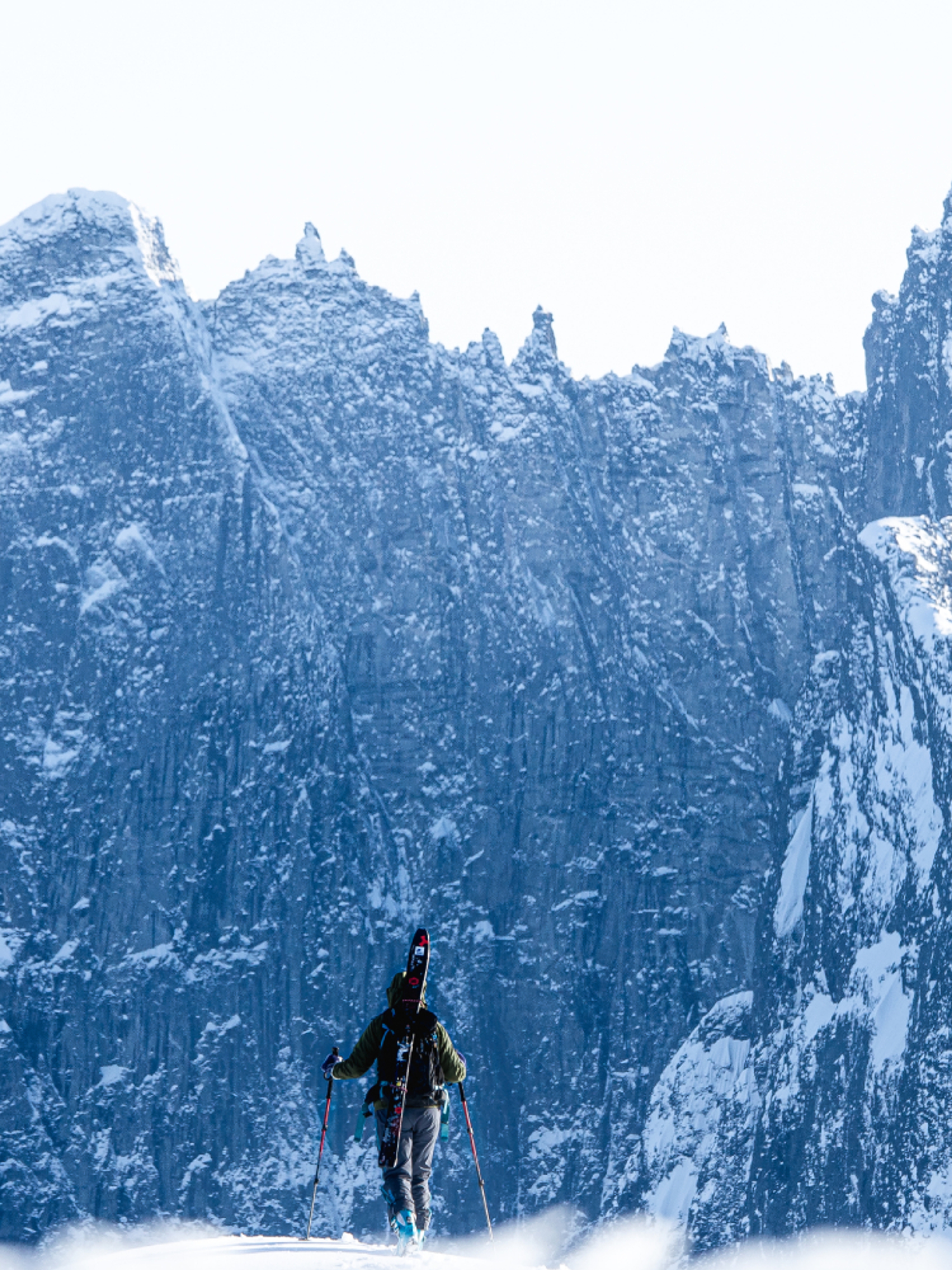 A person with skies looking at Trollveggen in Winter