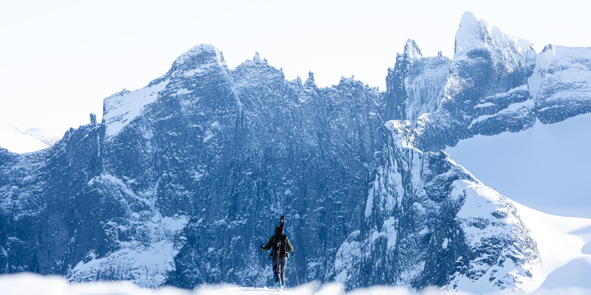 A person with skies looking at Trollveggen in Winter