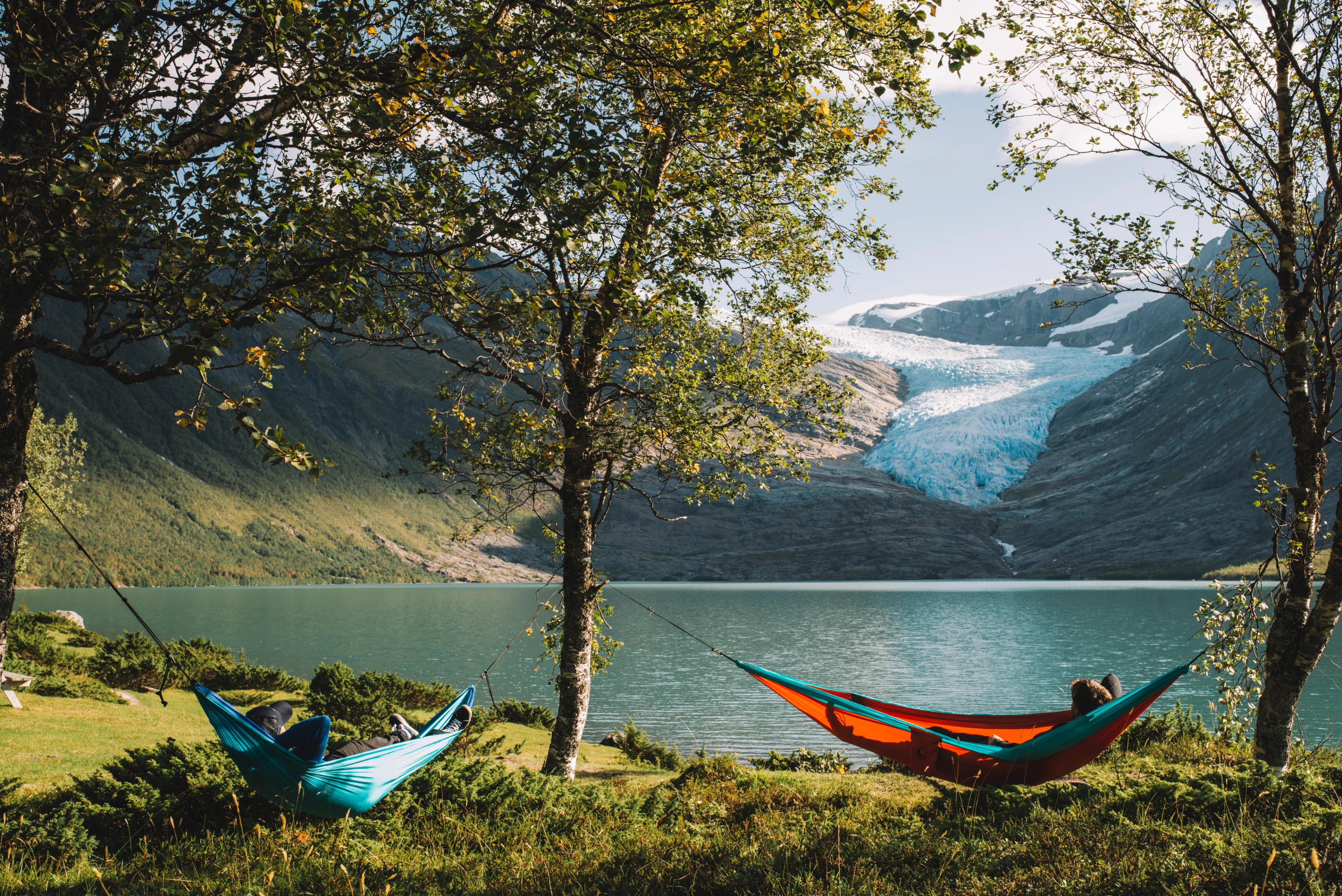 People in hammocks in front of the Svartisen glacier in Helgeland, Northern Norway