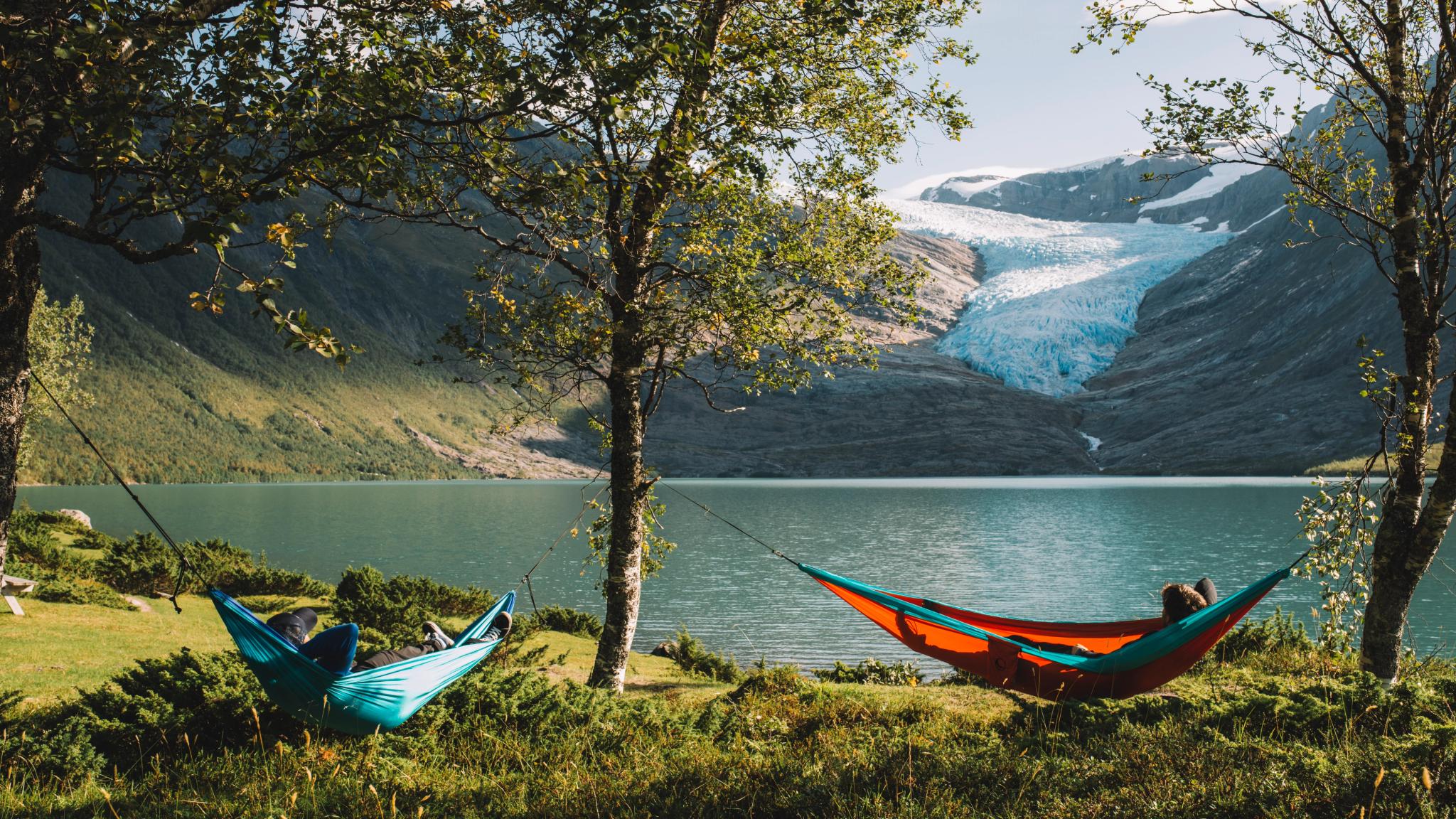People in hammocks in front of the Svartisen glacier in Helgeland, Northern Norway