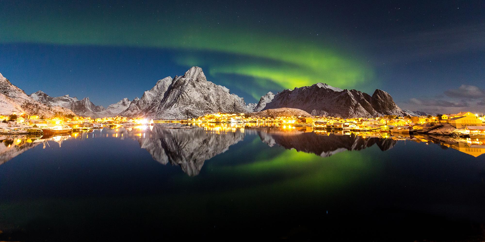 Vista de las auroras boreales sobre el pequeño pueblo de pescadores de Reine, en Lofoten, Norte de Noruega.