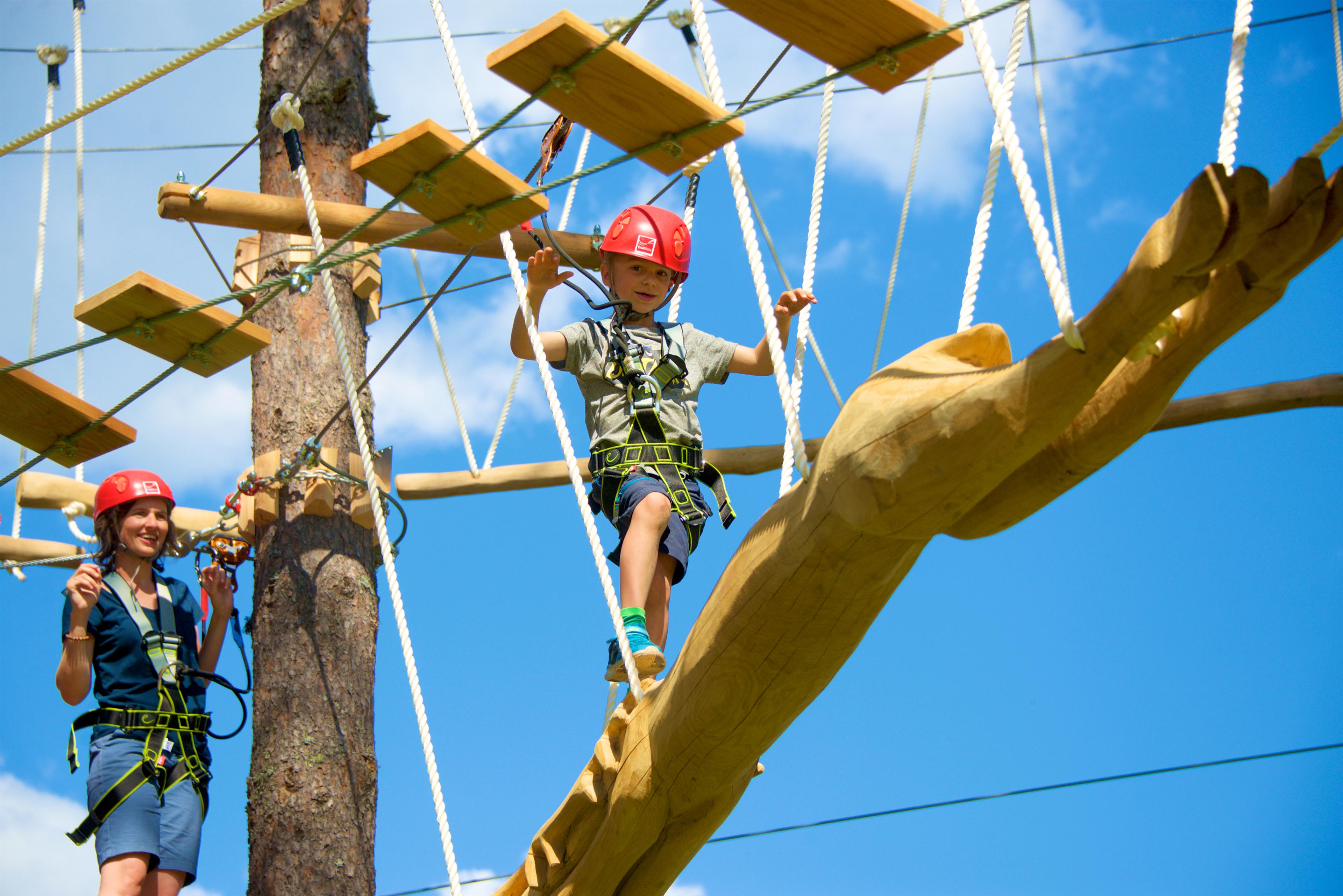 A boy balancing across a levitating log in Evje Klatrepark in Setesdal, Southern Norway