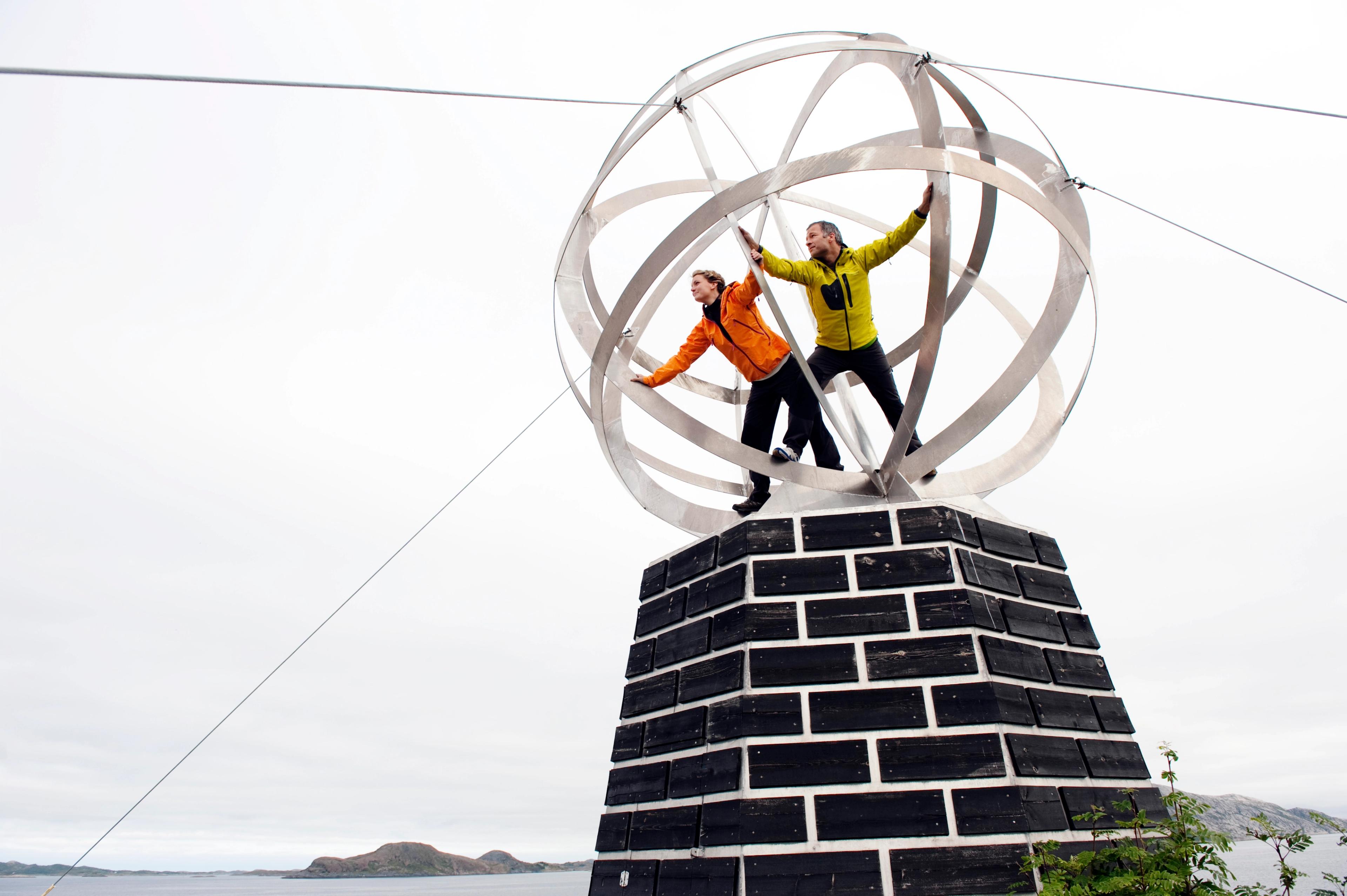 Two people standing inside a globe at the Helgeland coast in Northern Norway.
