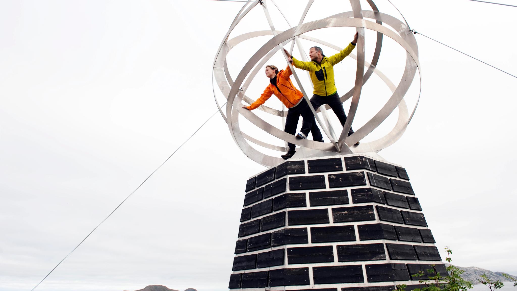 Two people standing inside a globe at the Helgeland coast in Northern Norway.