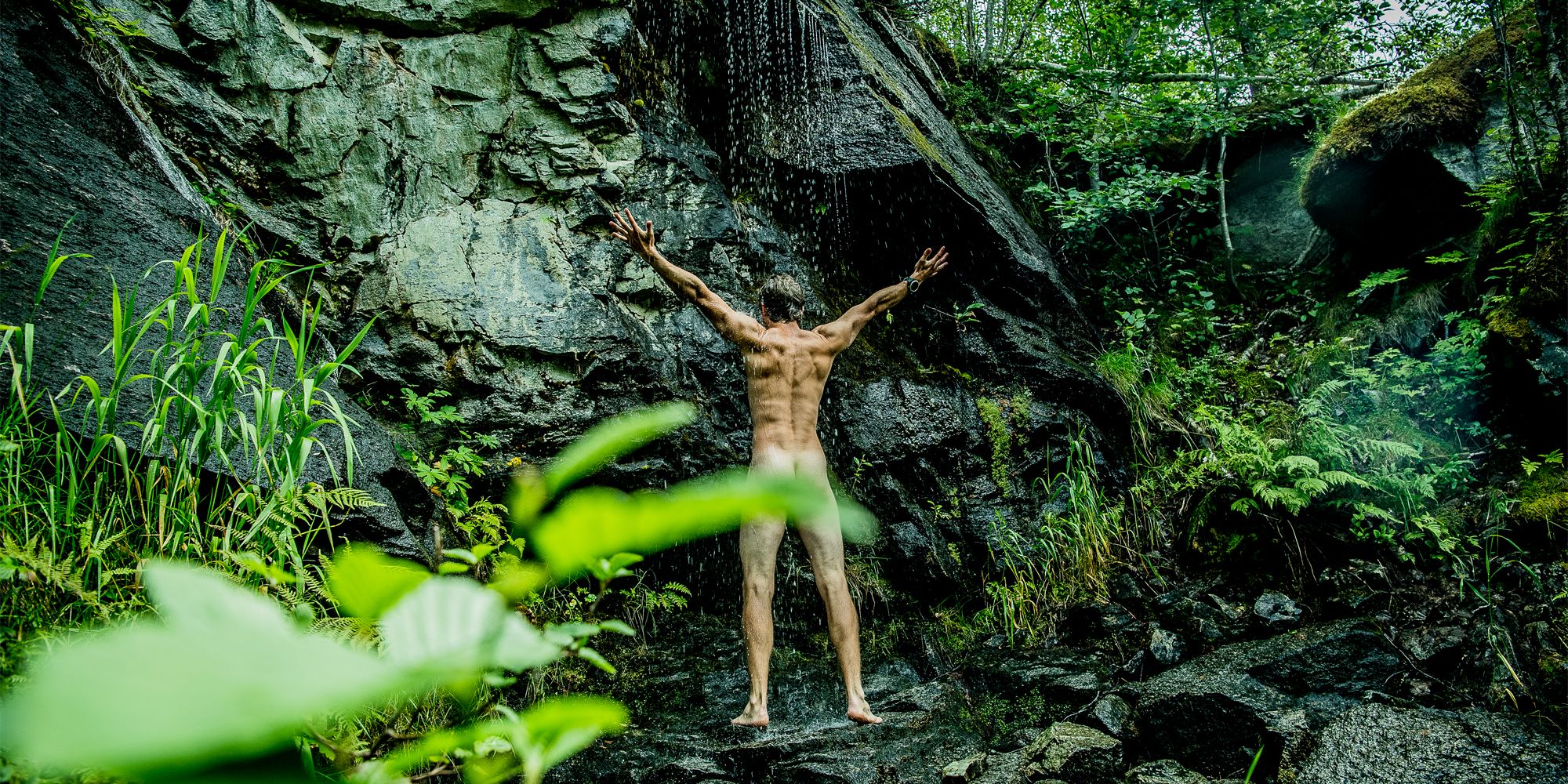 A man showering naked under a waterfall in Innerdalen, Norway
