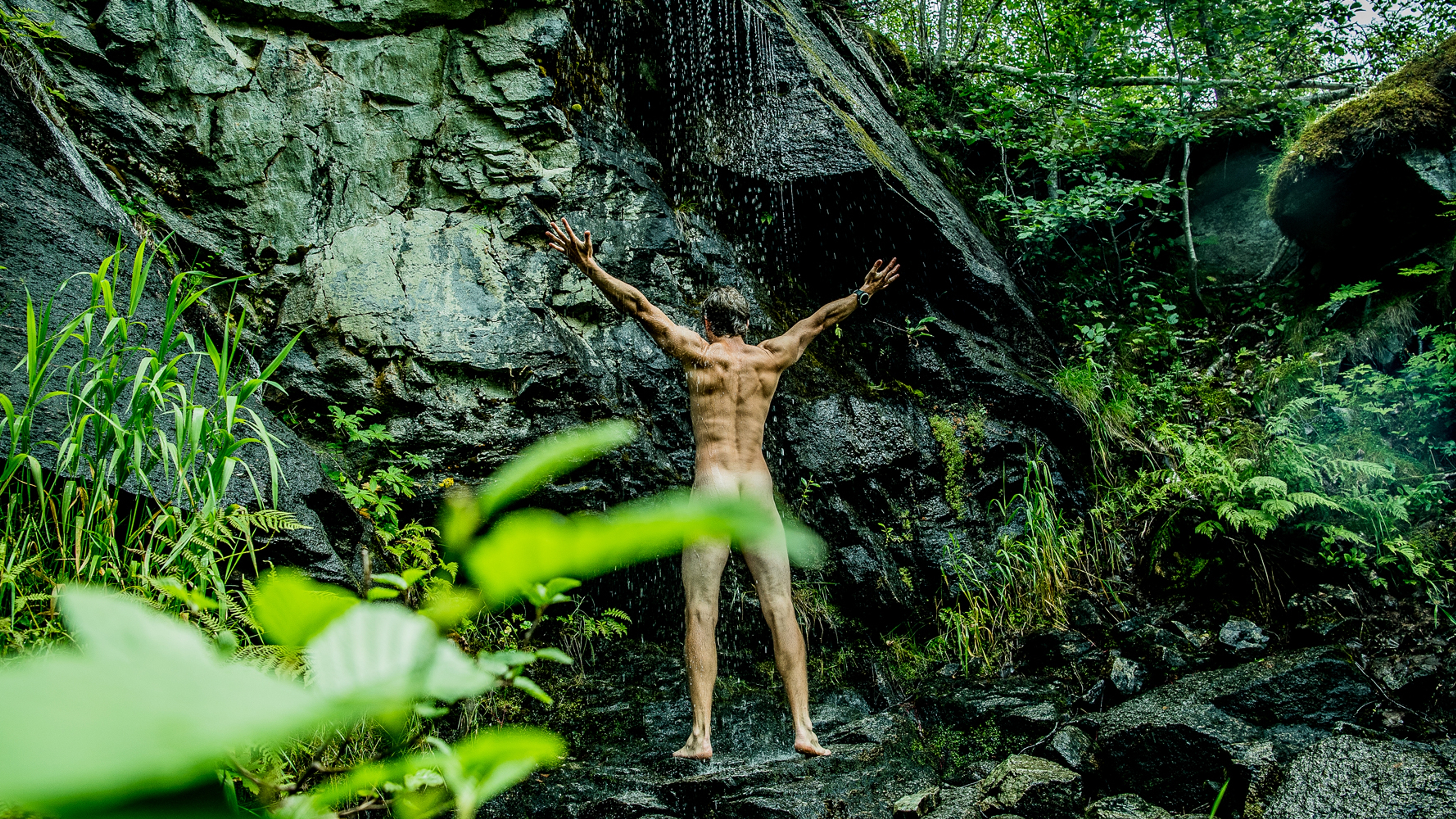 A man showering naked under a waterfall in Innerdalen, Norway