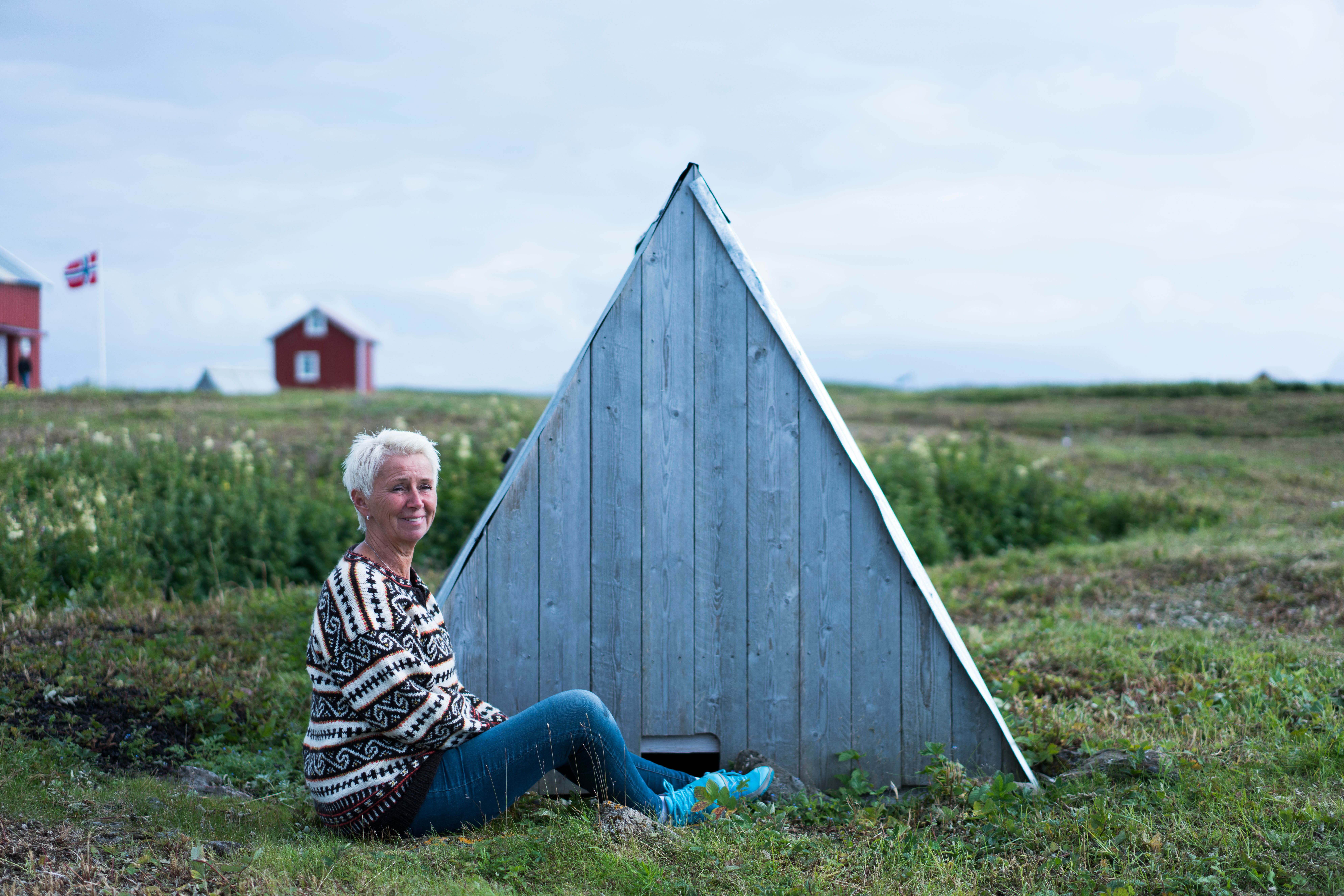A woman sitting outside a 'house' for eider ducks, at Lånan in the Vega Islands, Nordland