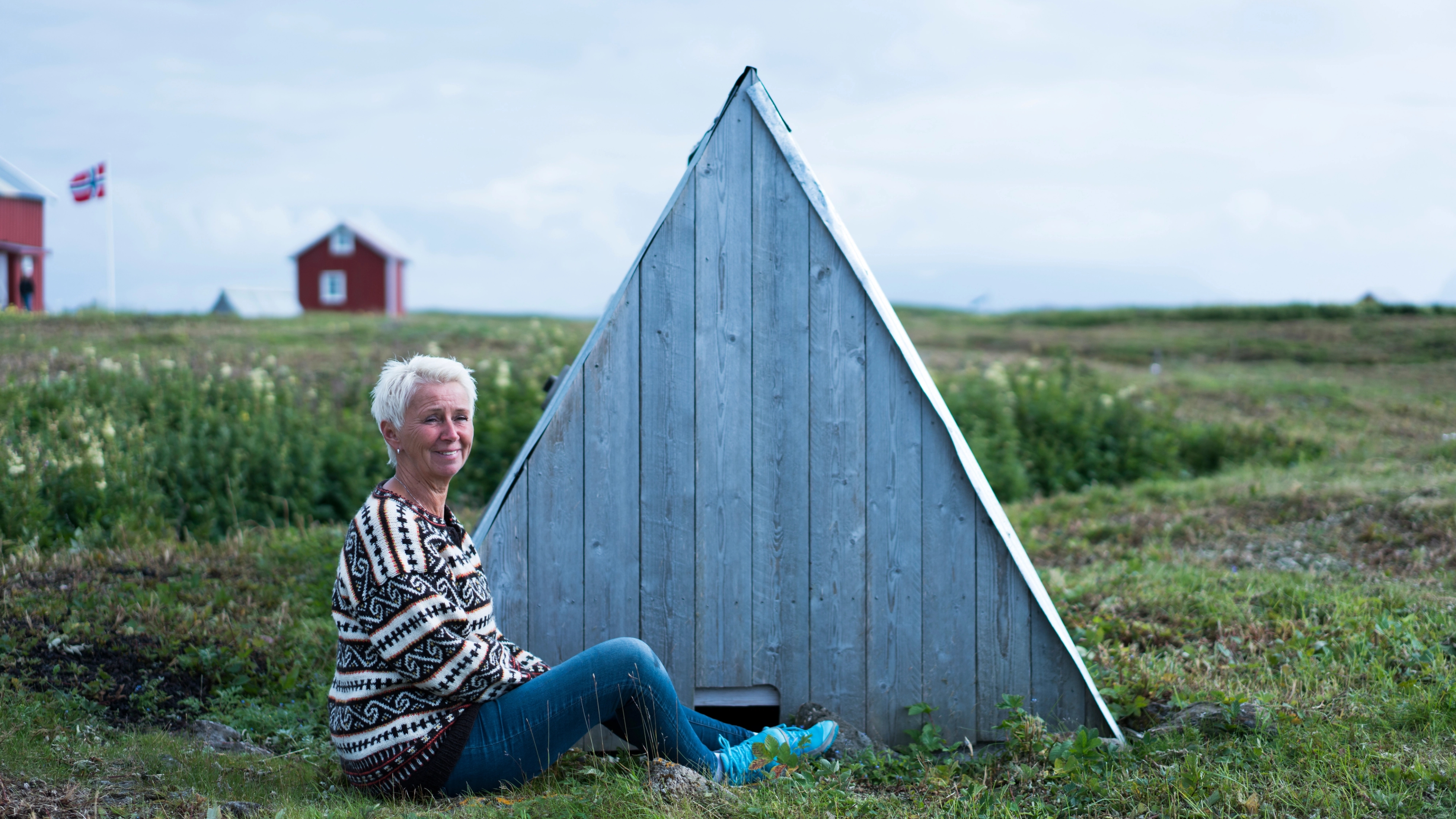 A woman sitting outside a 'house' for eider ducks, at Lånan in the Vega Islands, Nordland