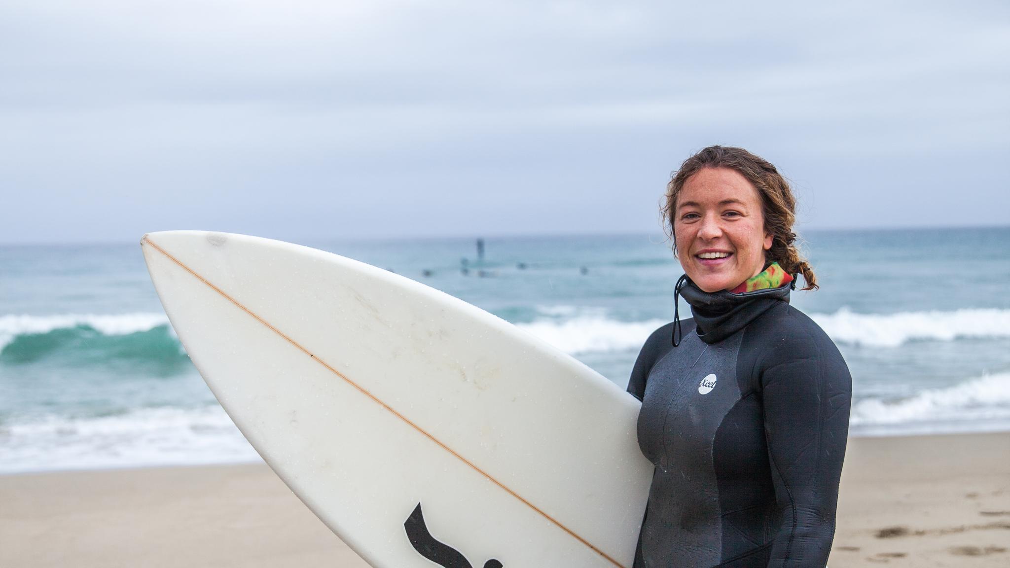 Woman holding a surf board on the Solstranden beach outside Stavanger in Fjord Norway
