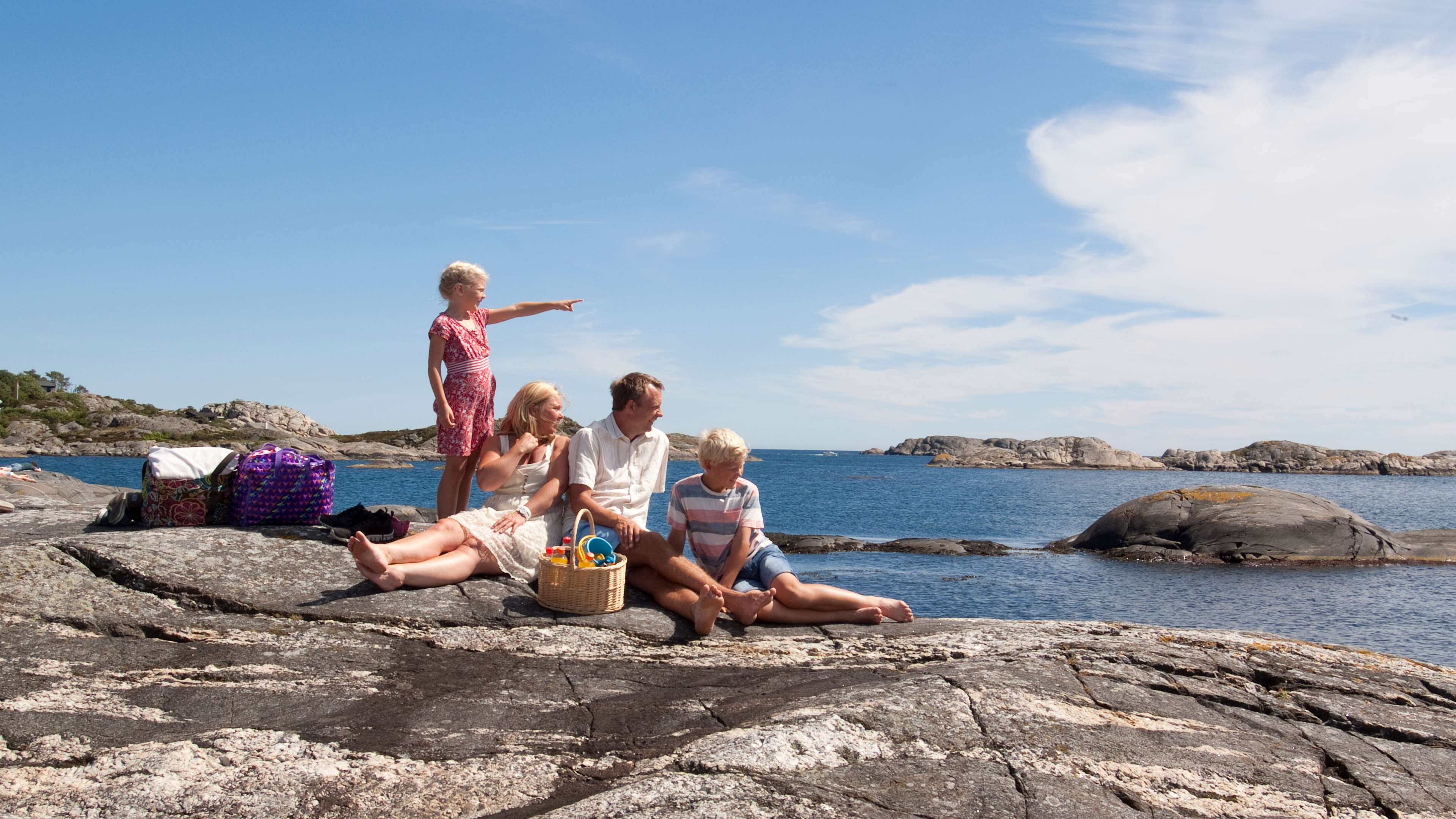 A family of four relaxing on an islet in Dynamittbukta in Grimstad, Southern Norway.