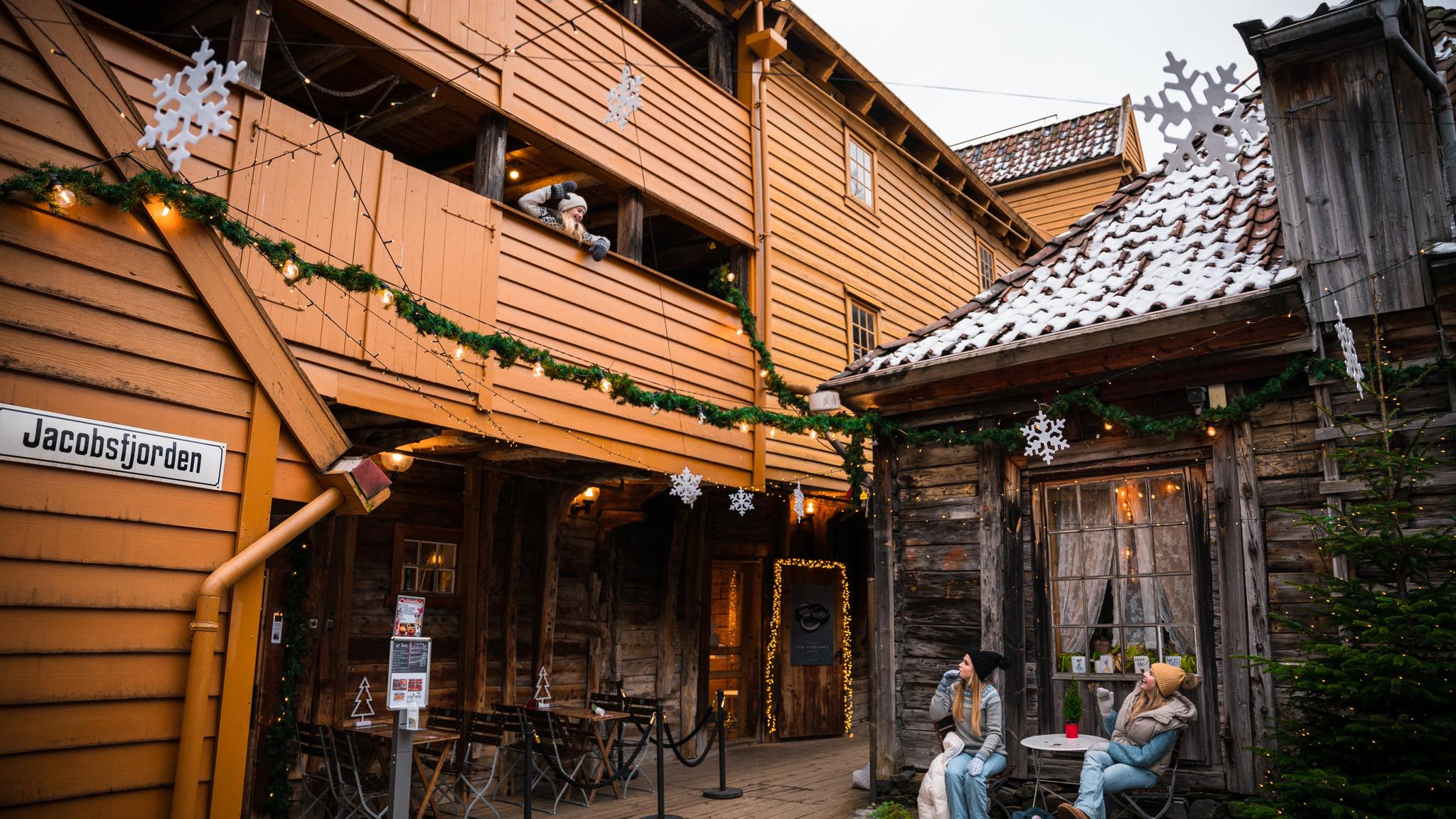 Three girls in the Christmas decorated passages of Bryggen wharf in Bergen, Fjord Norway