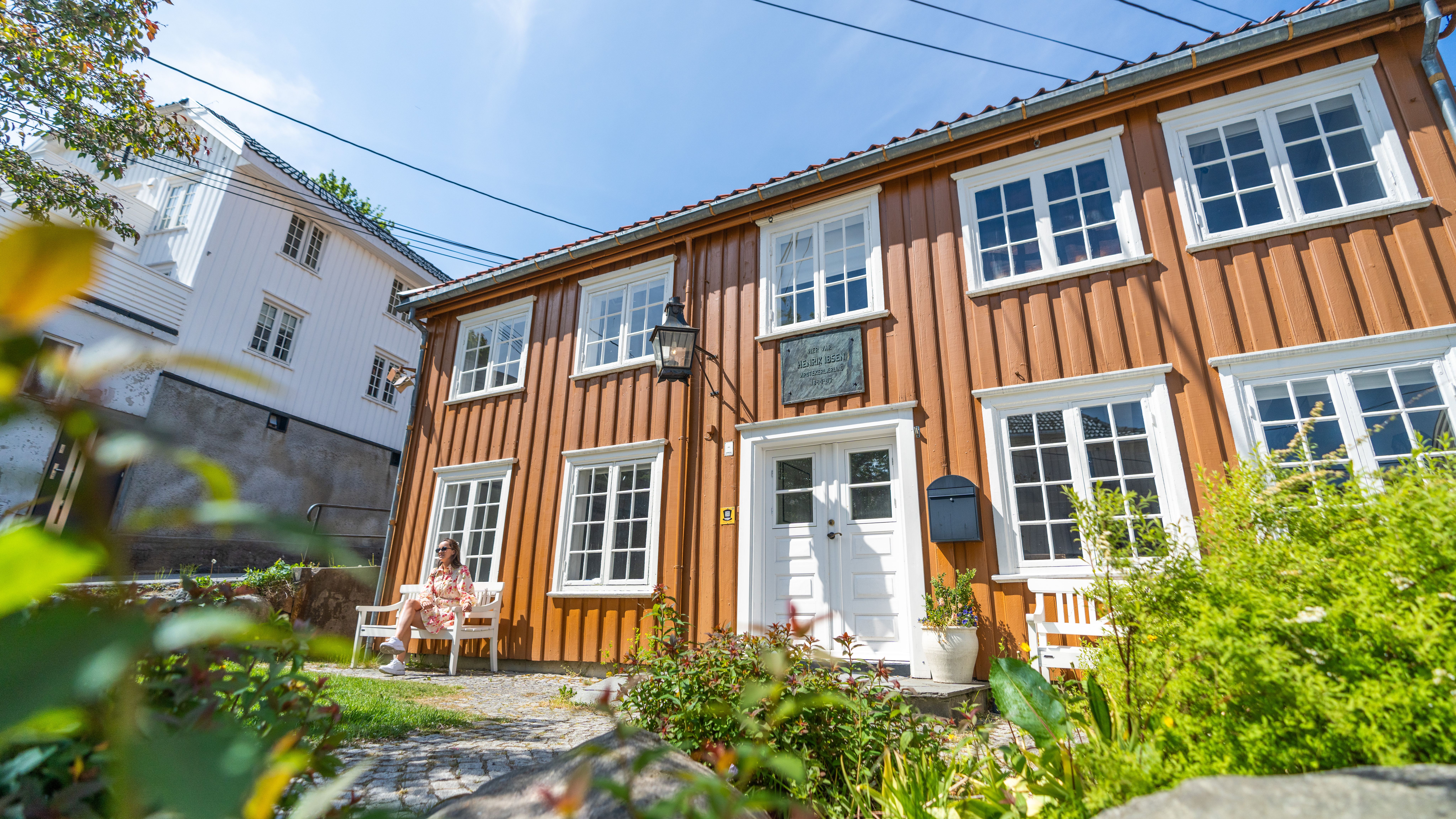 Girl sitting outside The Reiman House in Grimstad, where Henrik Ibsen once lived and worked