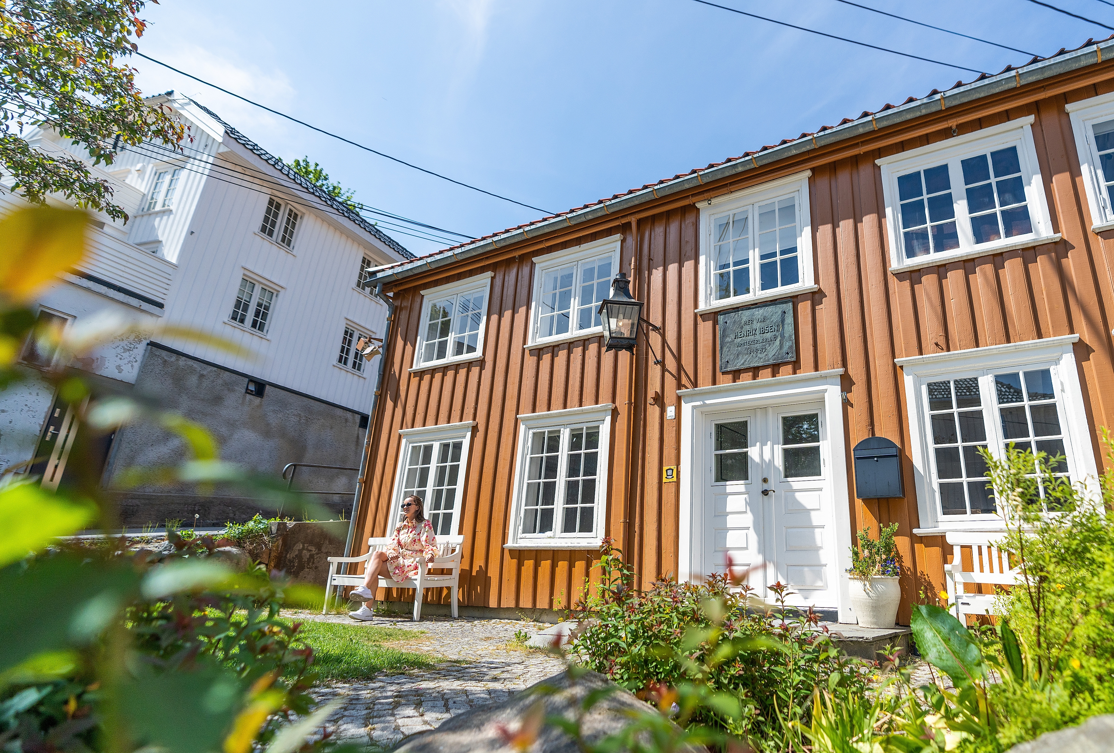Girl sitting outside The Reiman House in Grimstad, where Henrik Ibsen once lived and worked
