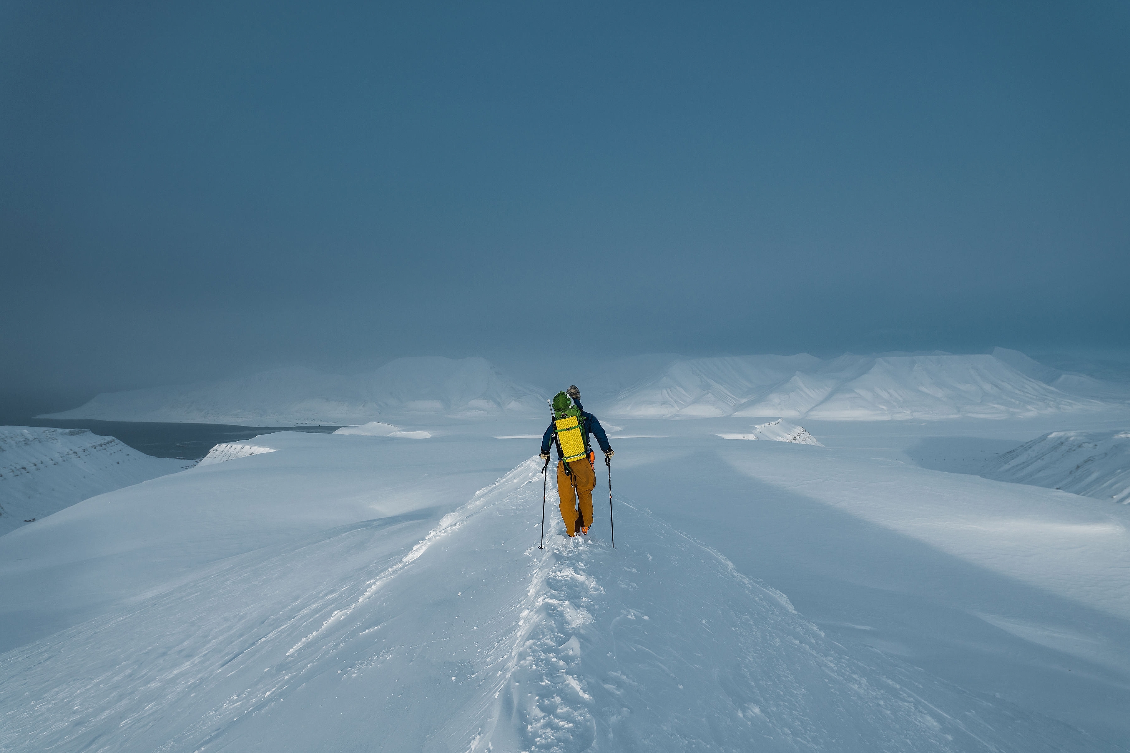 A person walking towards the alpine snow clad mountains in Svalbard