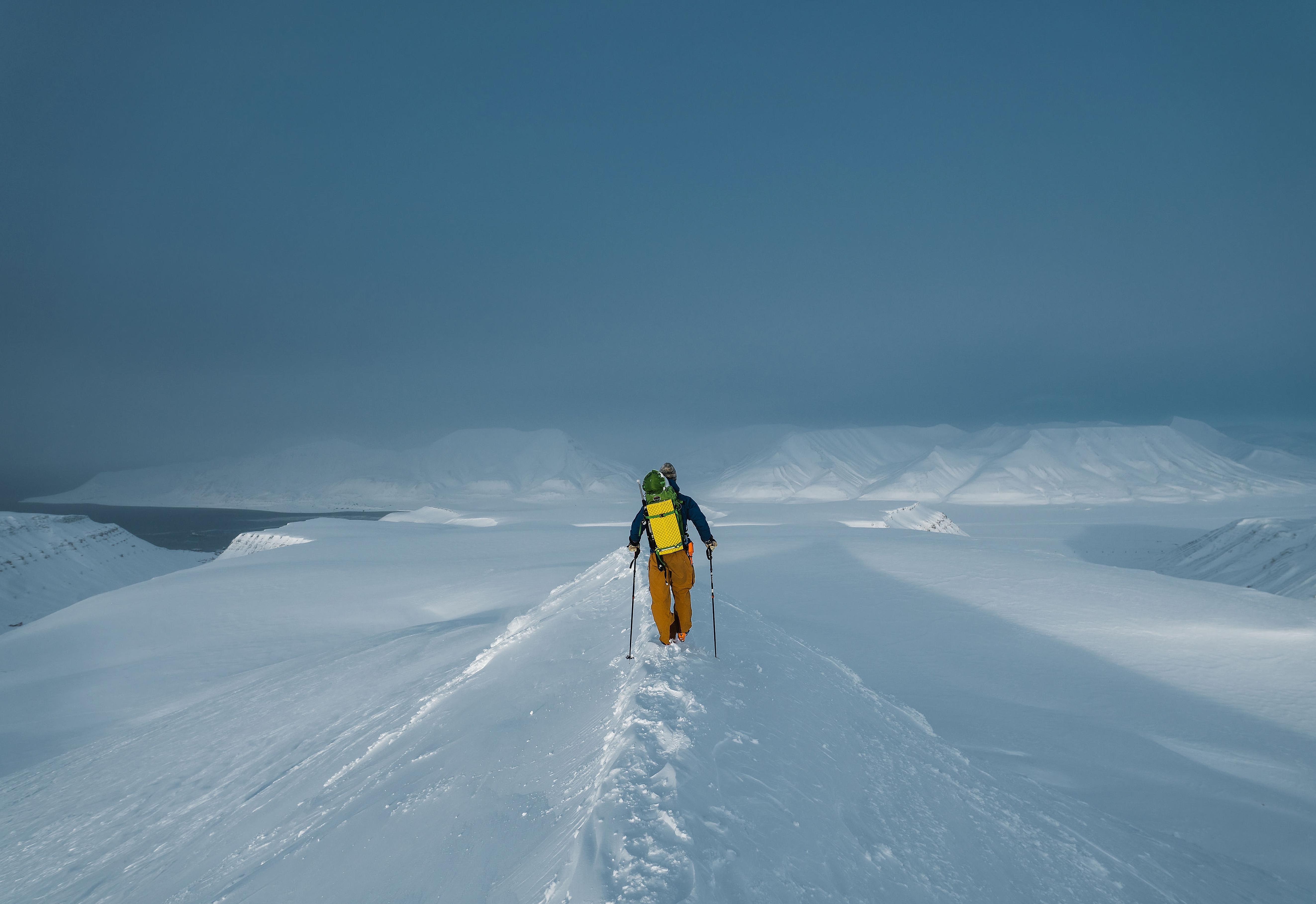 A person walking towards the alpine snow clad mountains in Svalbard