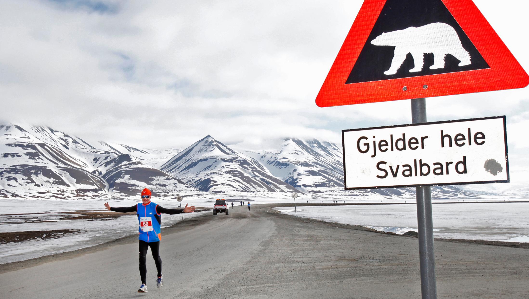 A marathon runner passing by a polar bear warning sign at Spitsbergen in Svalbard