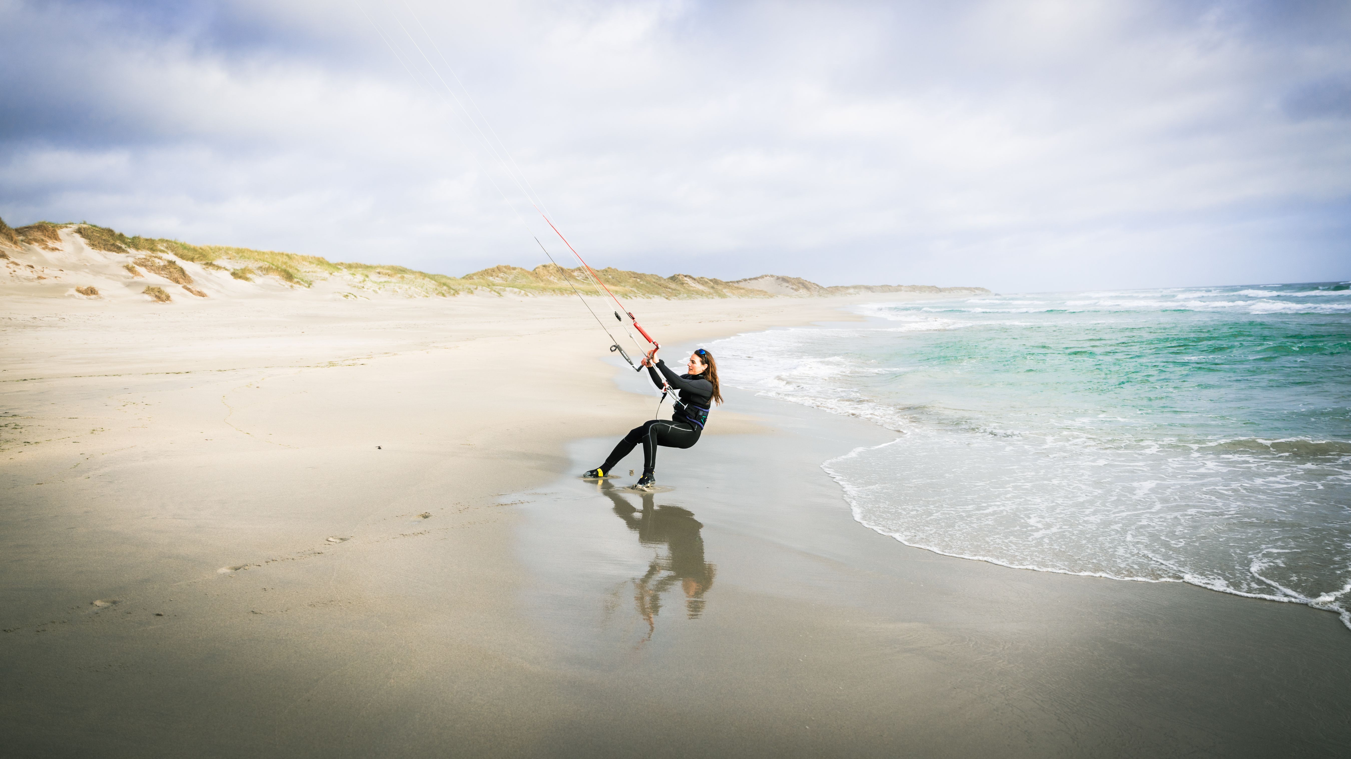 A woman kiting at a beach outside Stavanger, Fjord Norway.