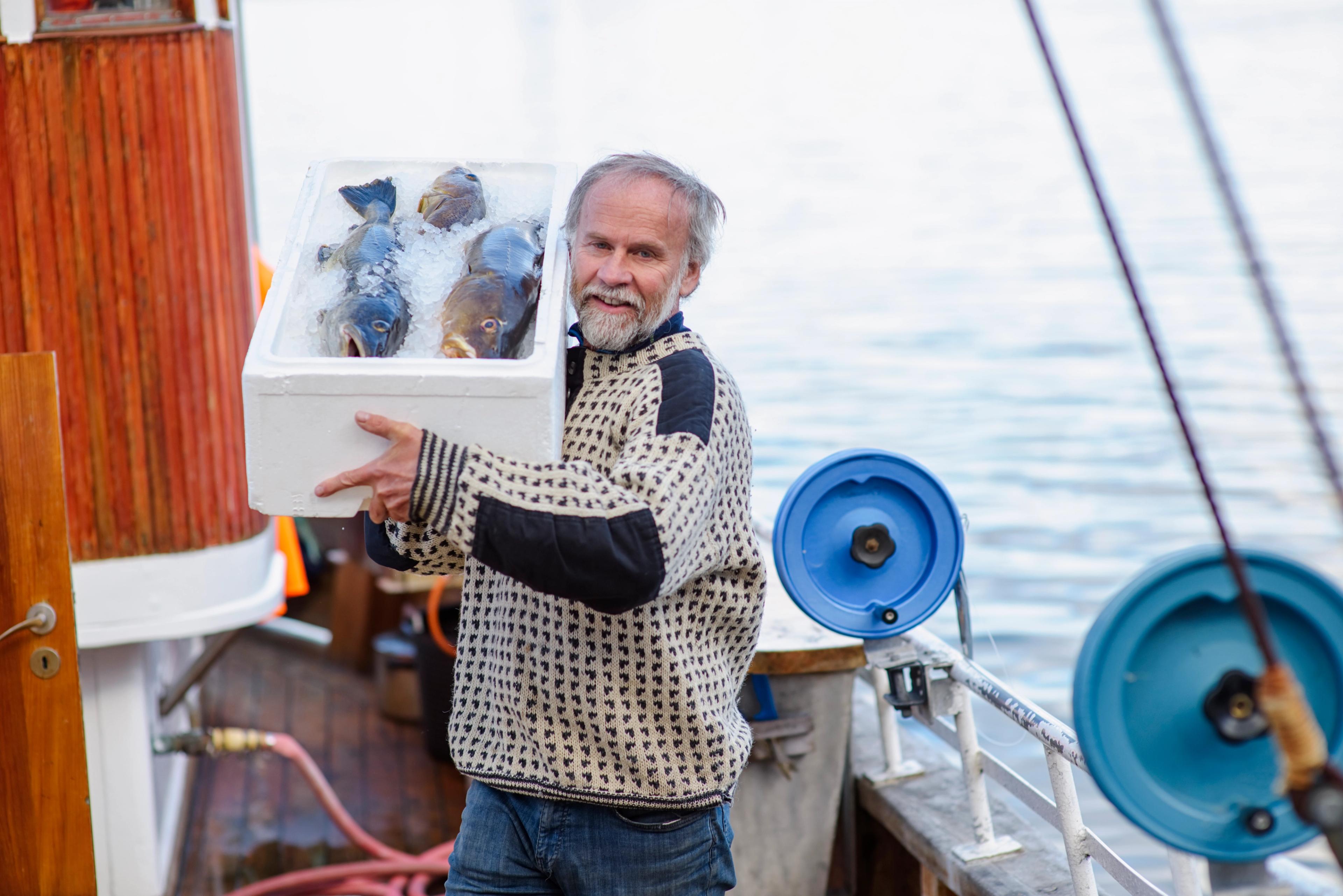 A man showing off three large fish in an iced box