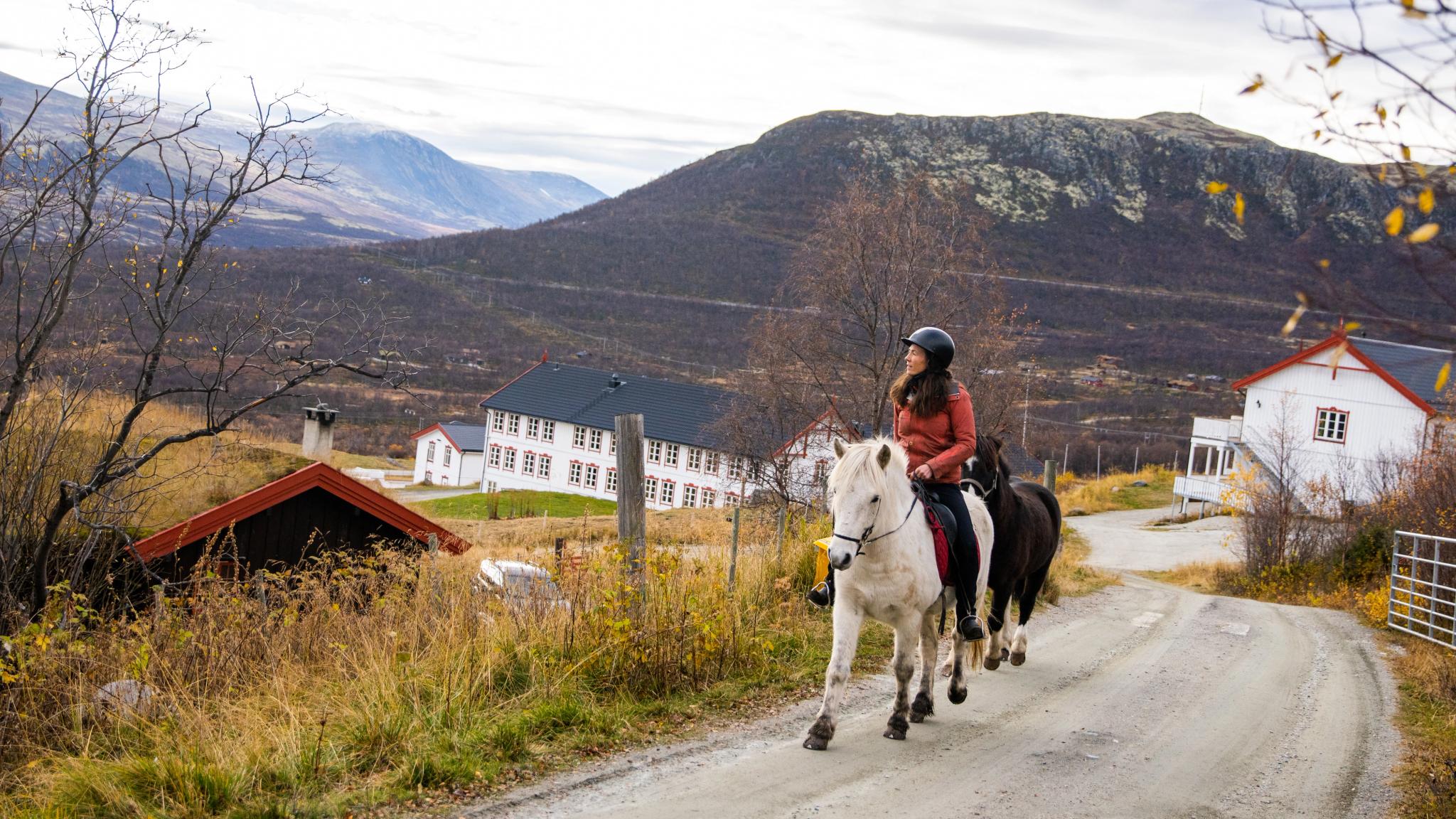 A woman sitting on a horse outside of Hjerkinn Fjellstue, Dovrefjell.
