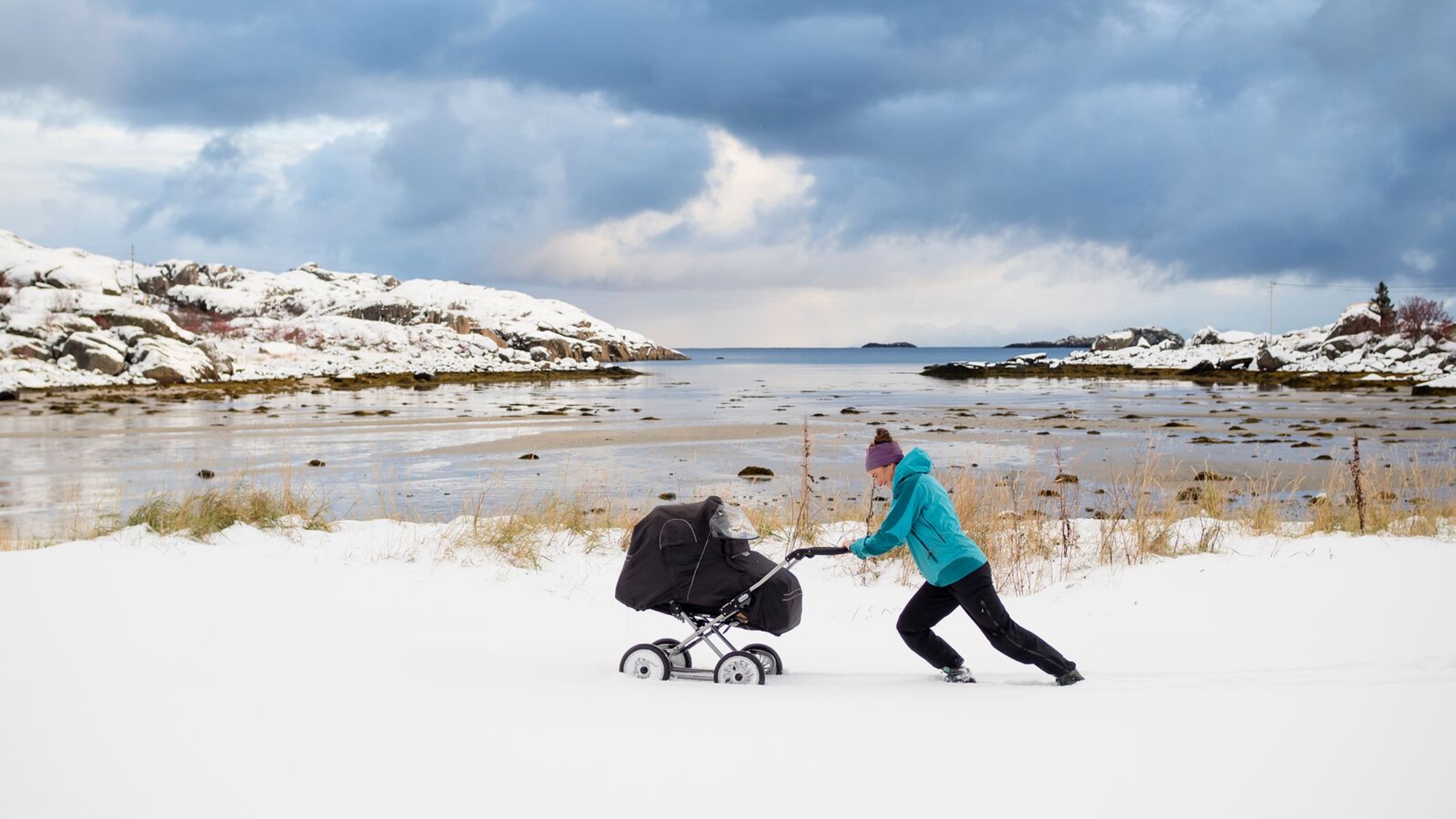 Woman pushing a pram in the snow in Northern Norway