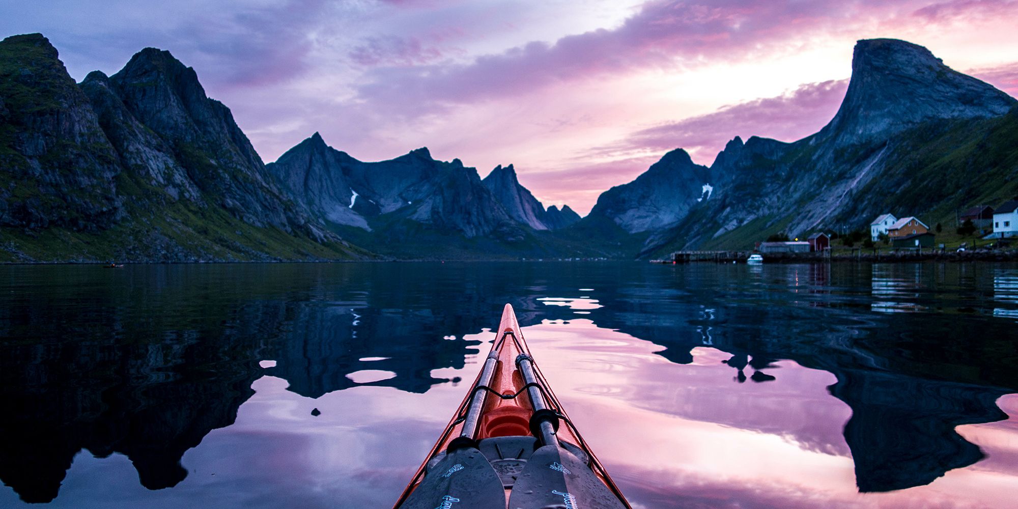 Étrave d’un kayak et versants escarpés sous le soleil de minuit à Moskenes, Lofoten, Norvège du Nord