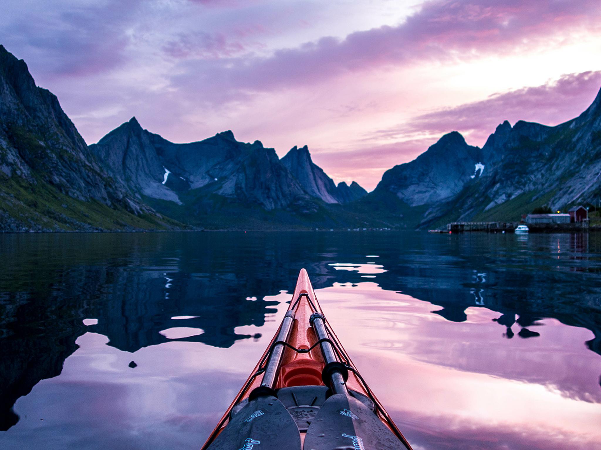 Étrave d’un kayak et versants escarpés sous le soleil de minuit à Moskenes, Lofoten, Norvège du Nord