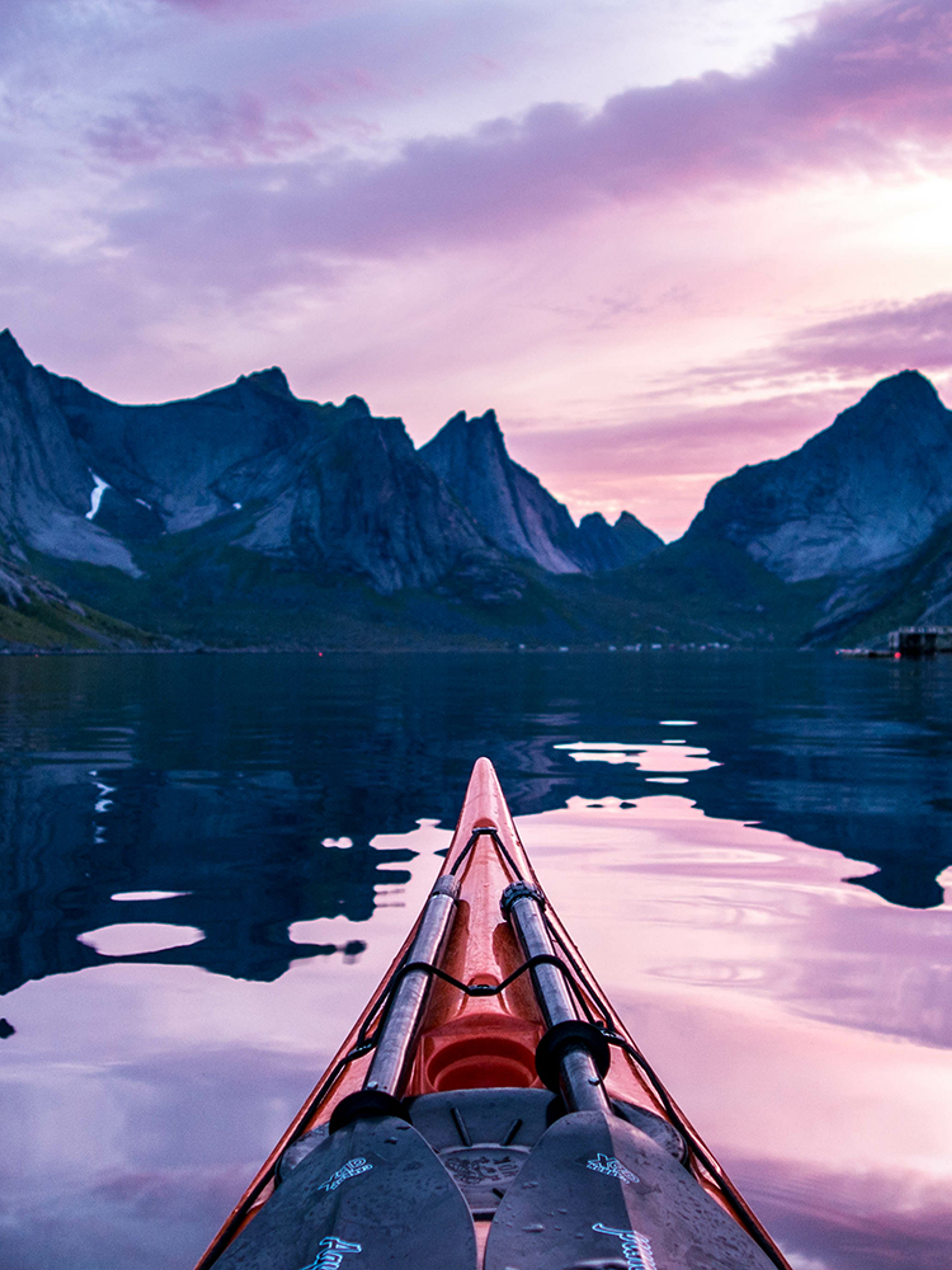 Étrave d’un kayak et versants escarpés sous le soleil de minuit à Moskenes, Lofoten, Norvège du Nord