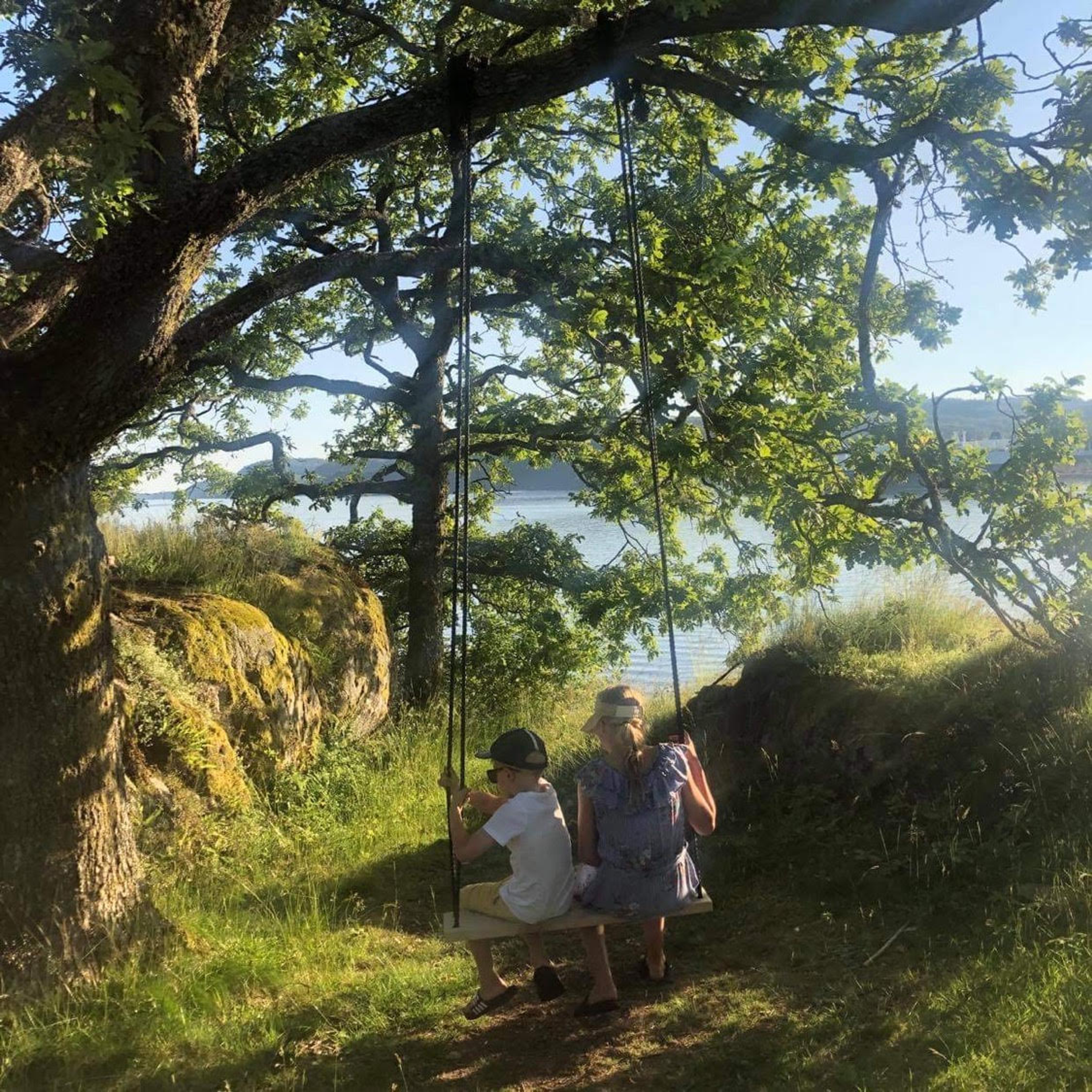 Two children on an outdoor swing in Rosfjord, Southern Norway