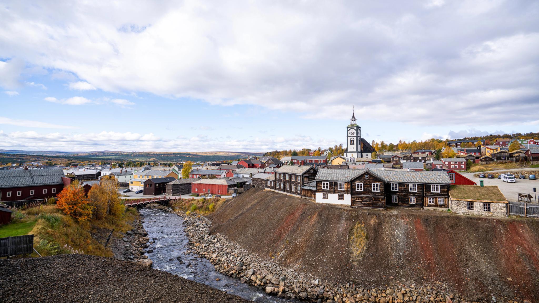 An overview of Røros with wooden houses, a river and a church.
