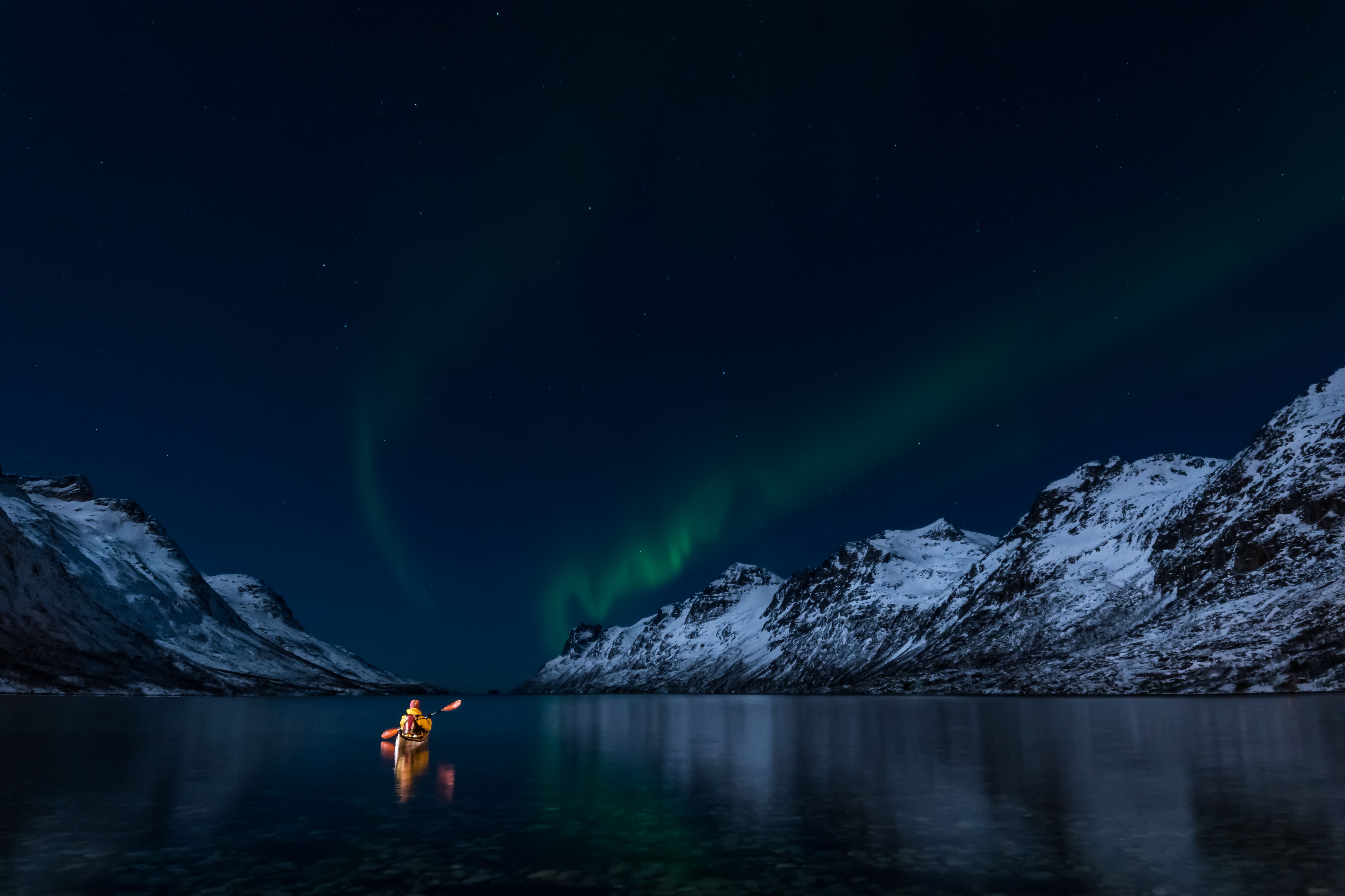 Una persona navega a bordo de un kayak bajo las auroras boreales en Lofoten, Norte de Noruega.