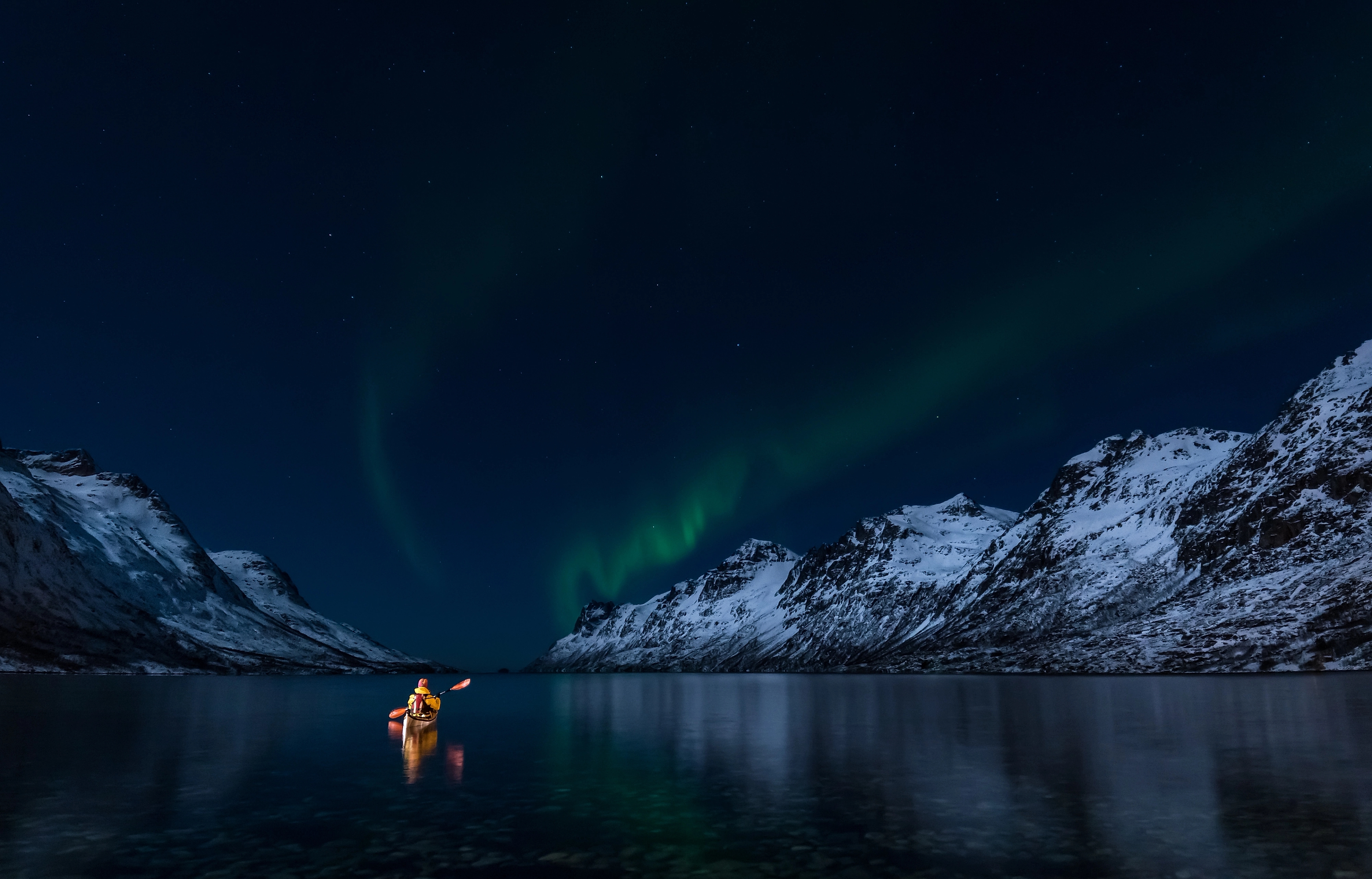 Kayakiste sous une aurore boréale dans les Lofoten, en Norvège du Nord