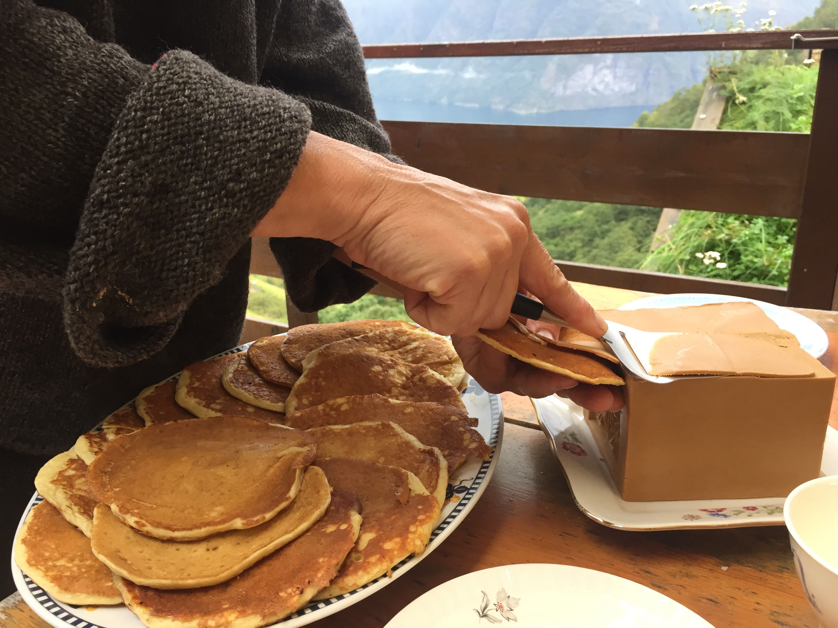 Person slicing brown cheese for pancakes