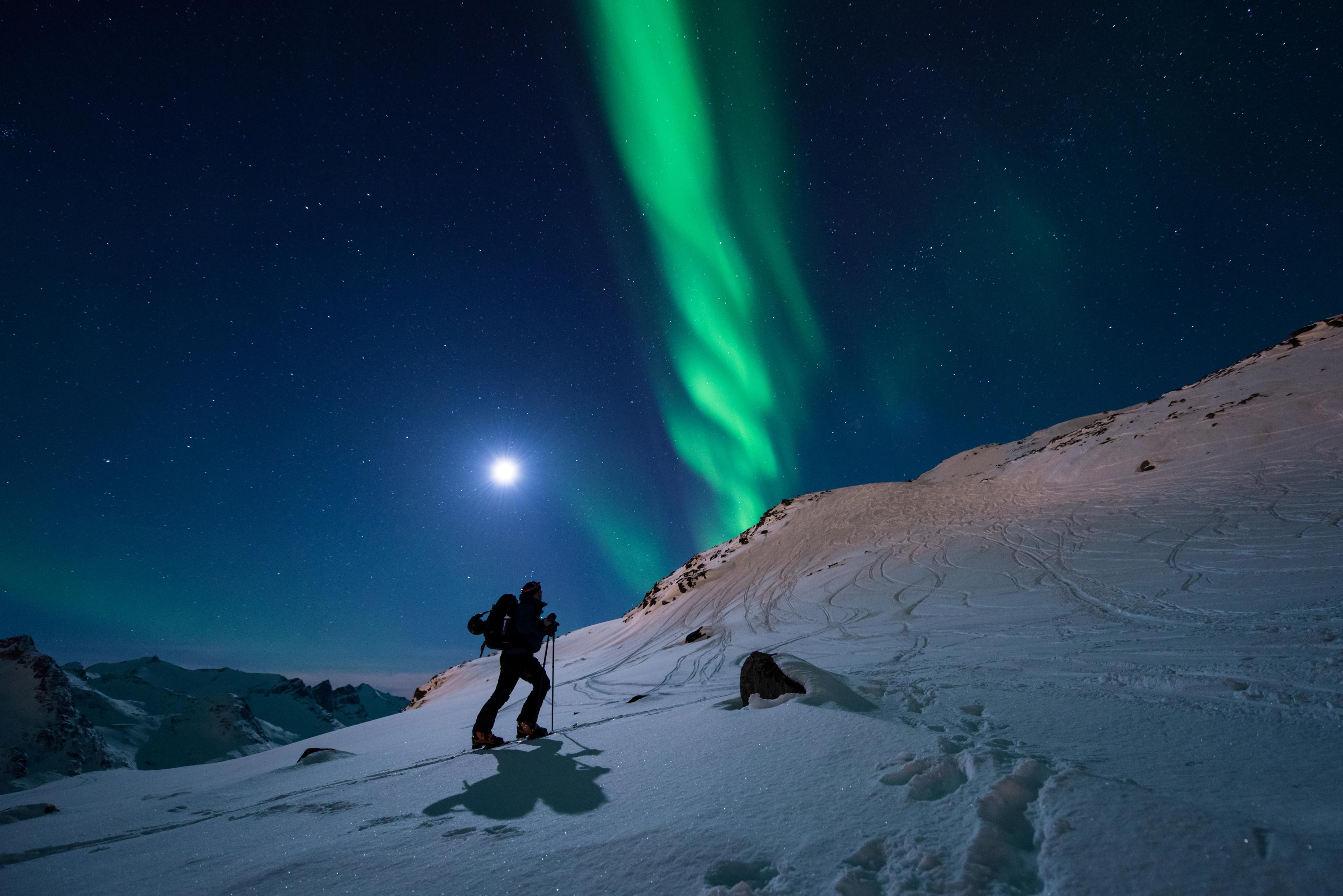 A man is ski touring under the northern lights in Northern Norway