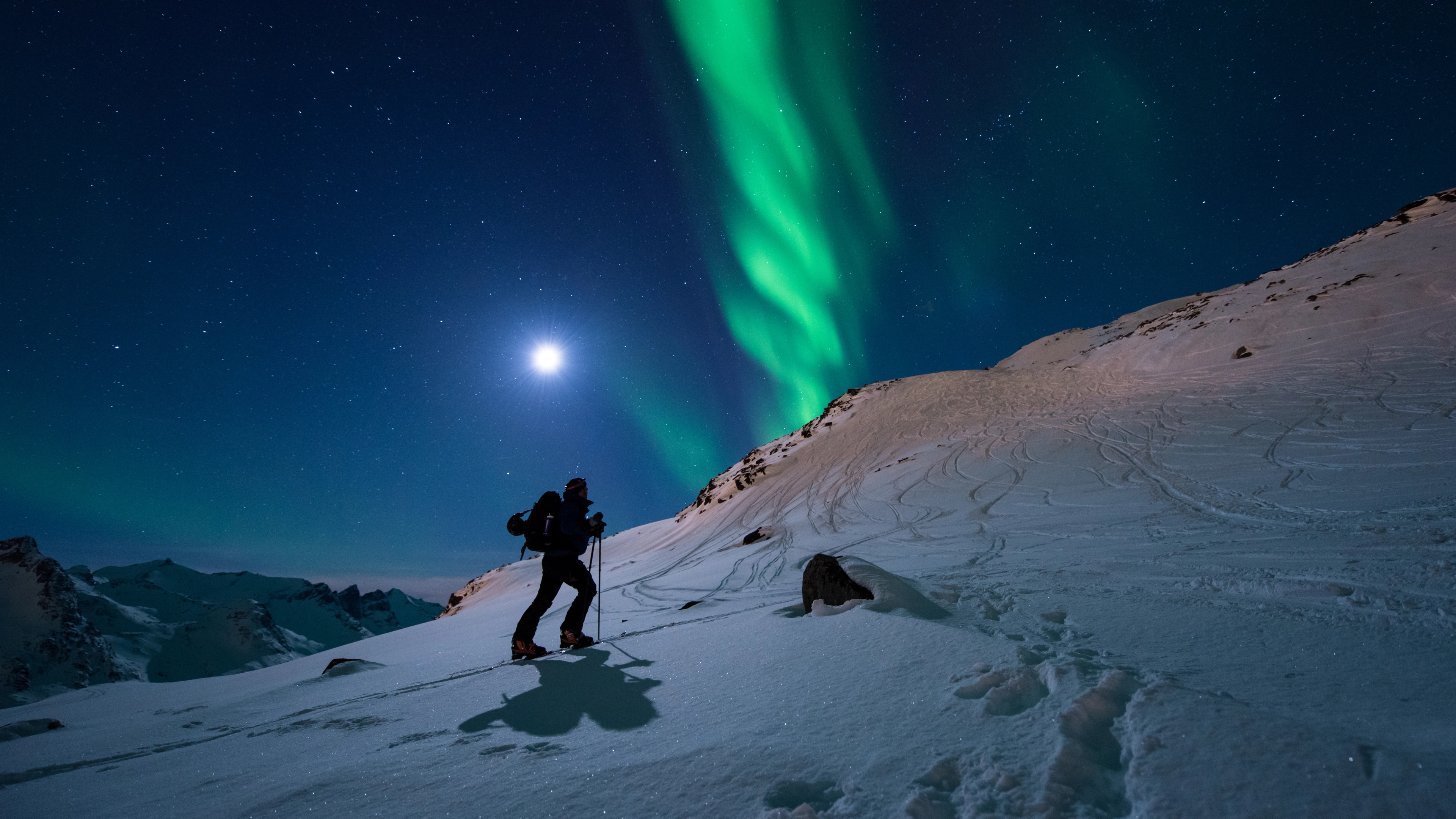 A man is ski touring under the northern lights in Northern Norway