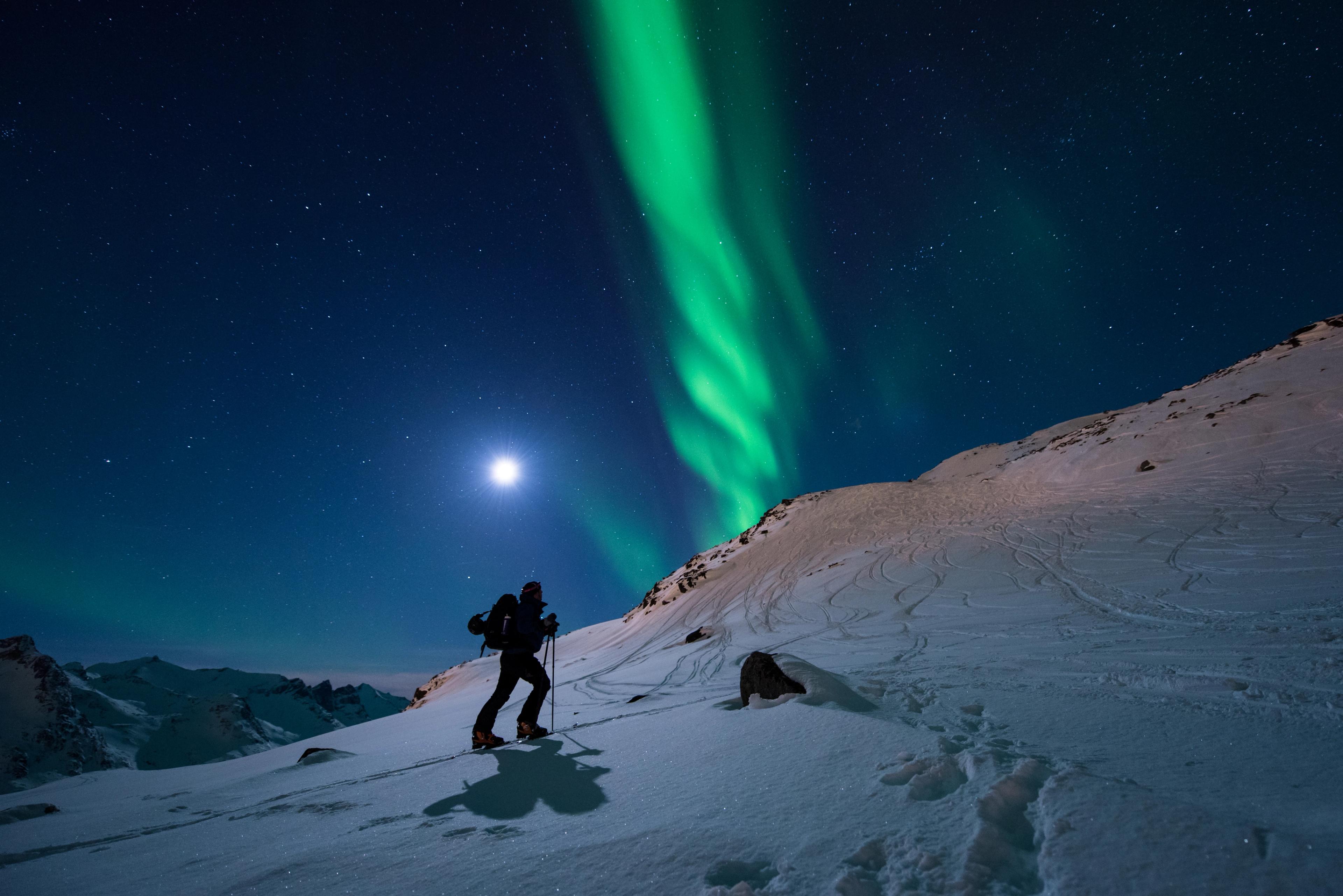 A man is ski touring under the northern lights in Northern Norway