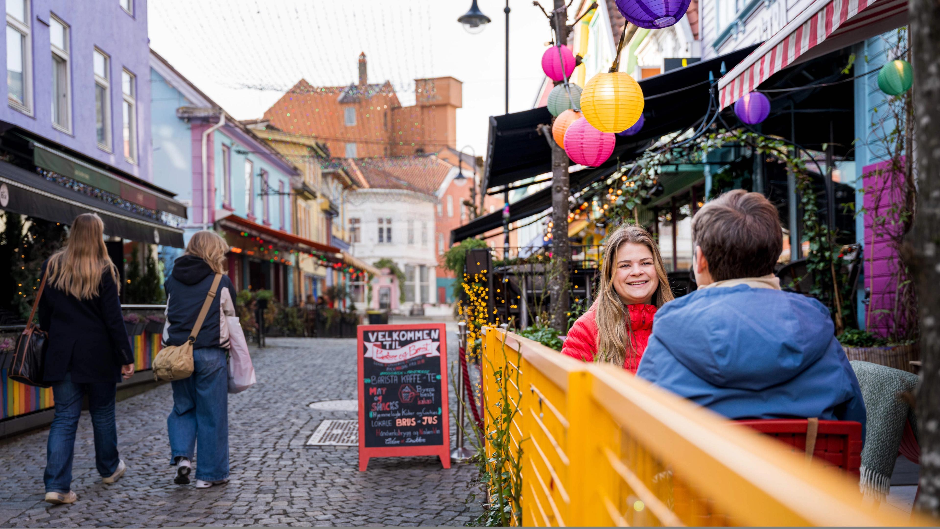 Two friends sitting outside at Bøker og Børst in Fargegaten street, The colour street